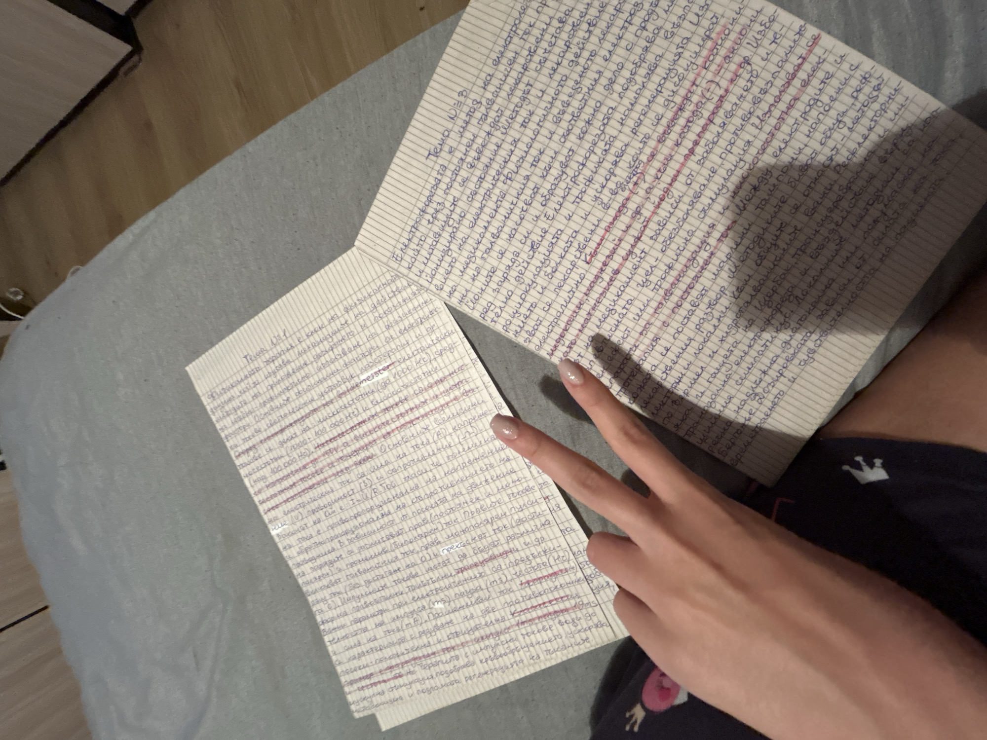 Person displays peace sign while holding handwritten notes on bed