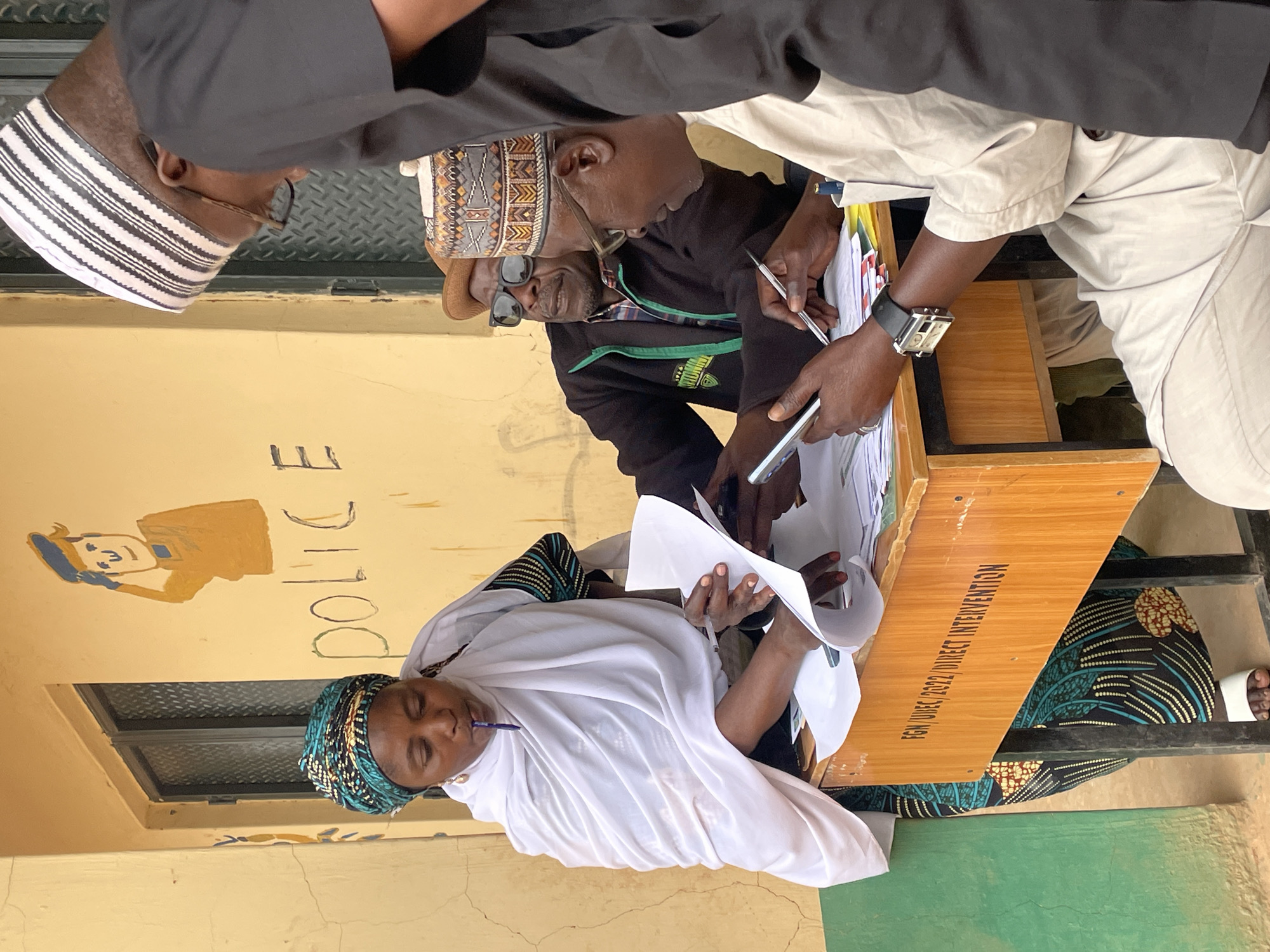 Groups gather around tables examining documents in Jos, Nigeria