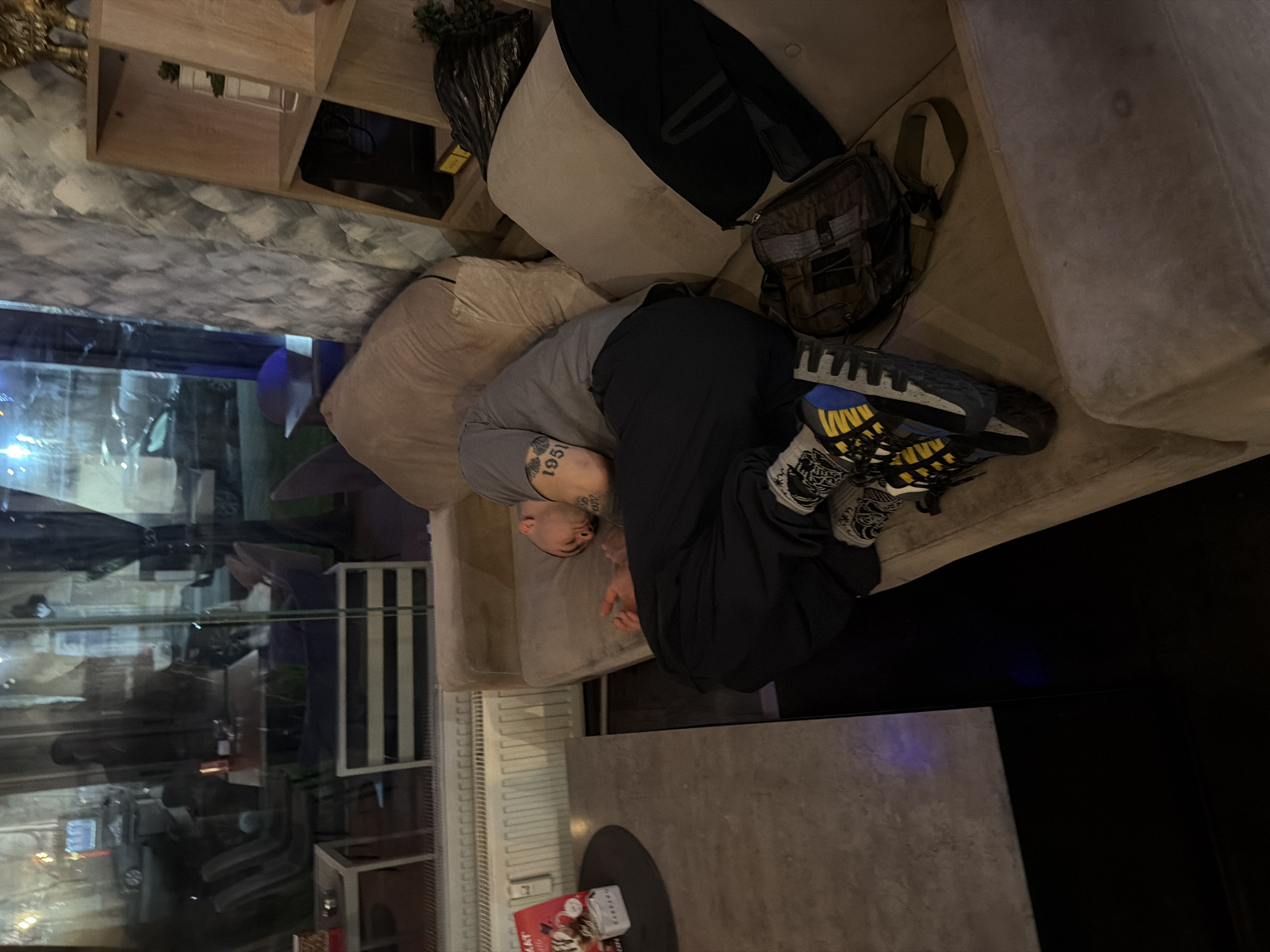 Man relaxes on sofa at midnight in Pernik, Bulgaria