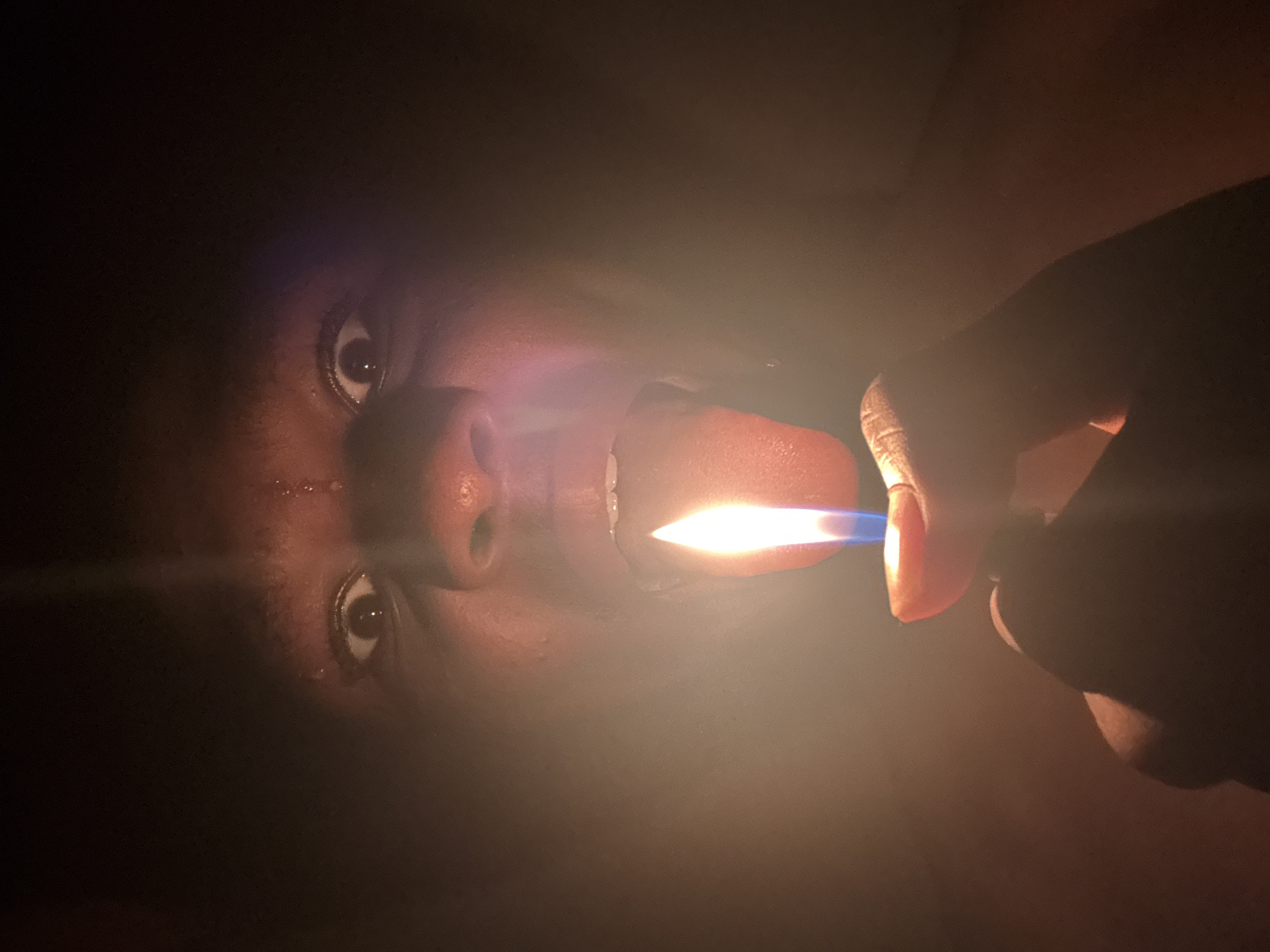 Person photographed with lighter, hands obscuring face in Onitsha