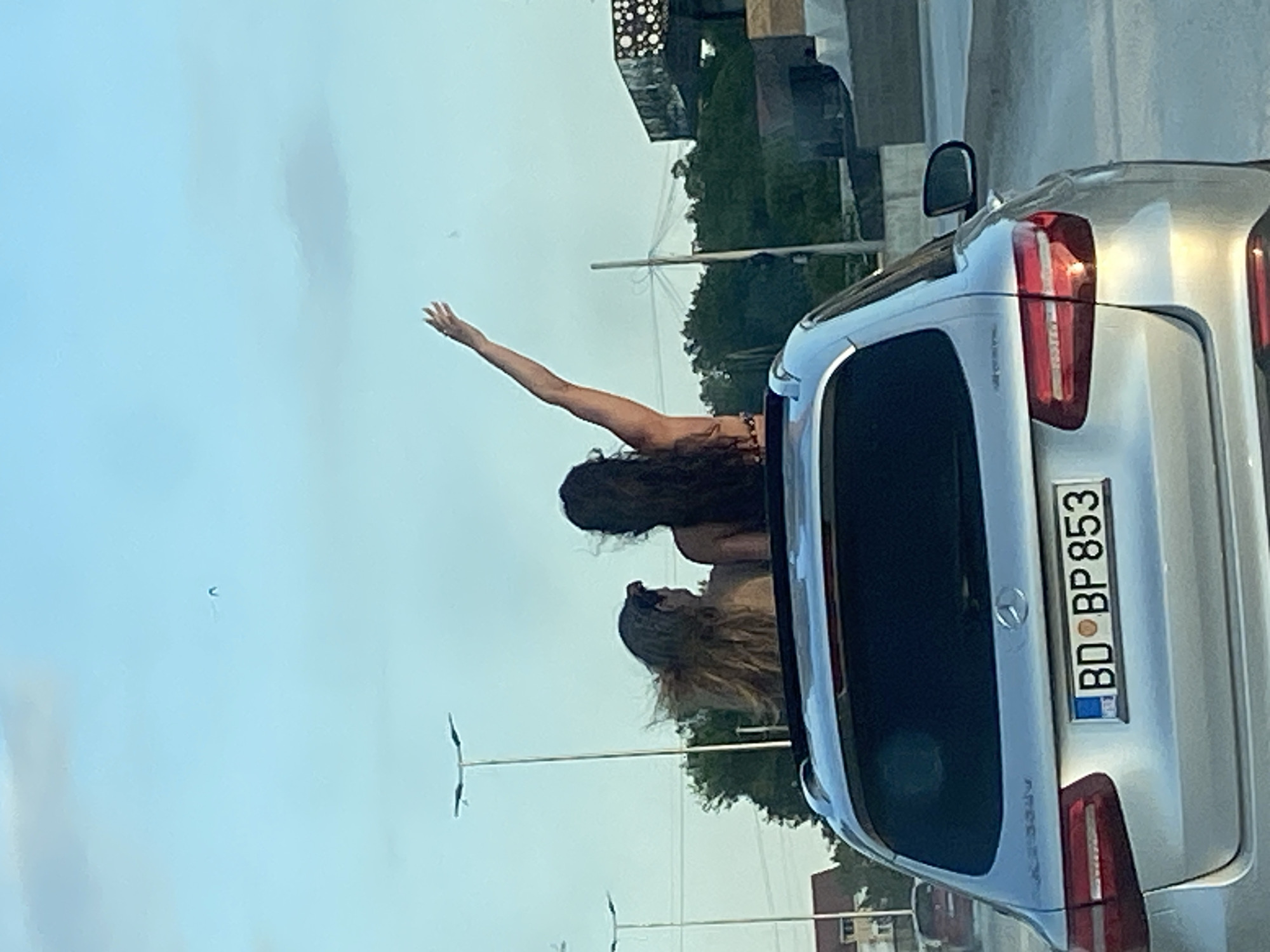 Women celebrate through sunroof on dusty Montenegro road