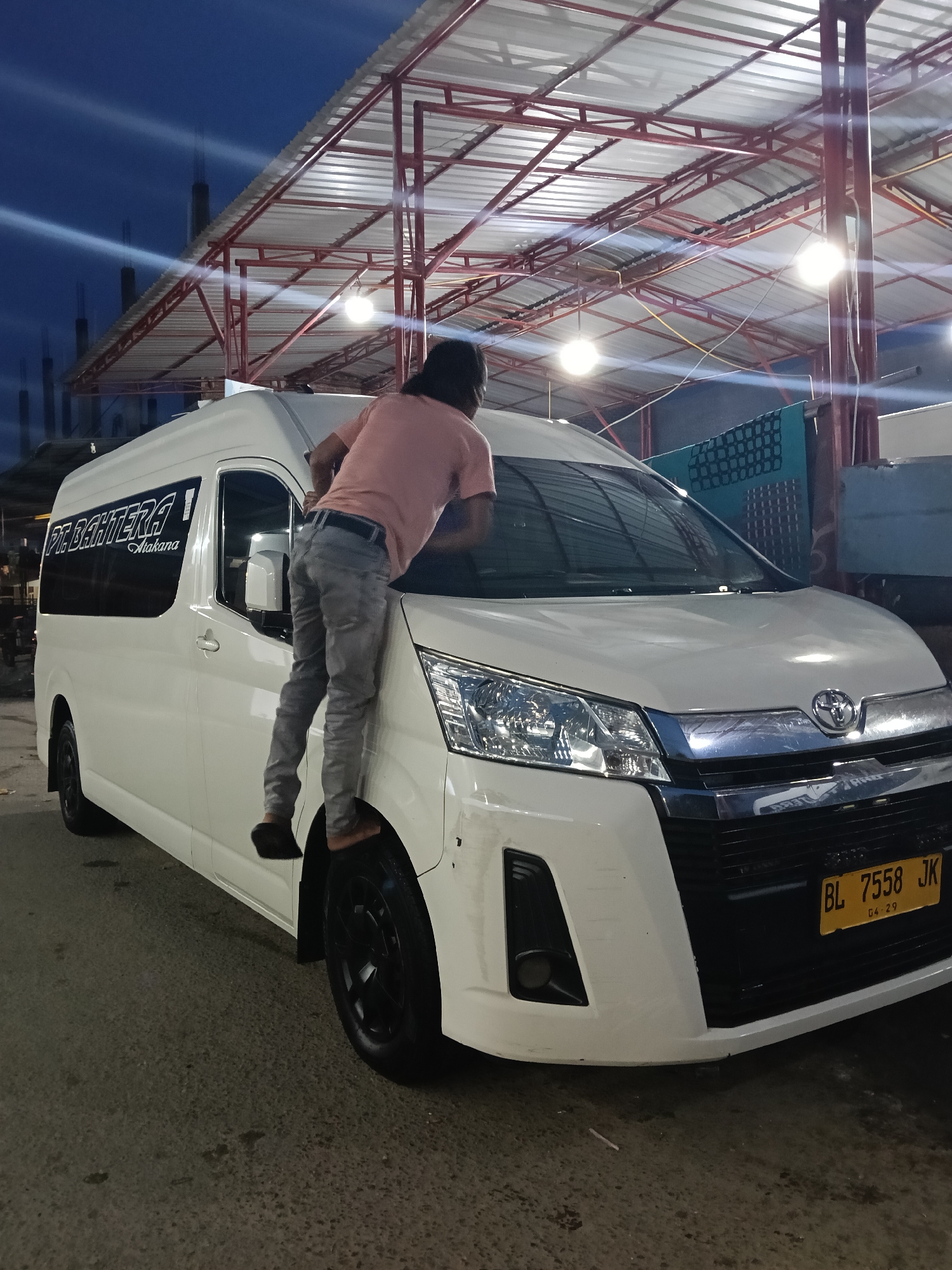 Man washes commercial van at night car wash in Indonesia