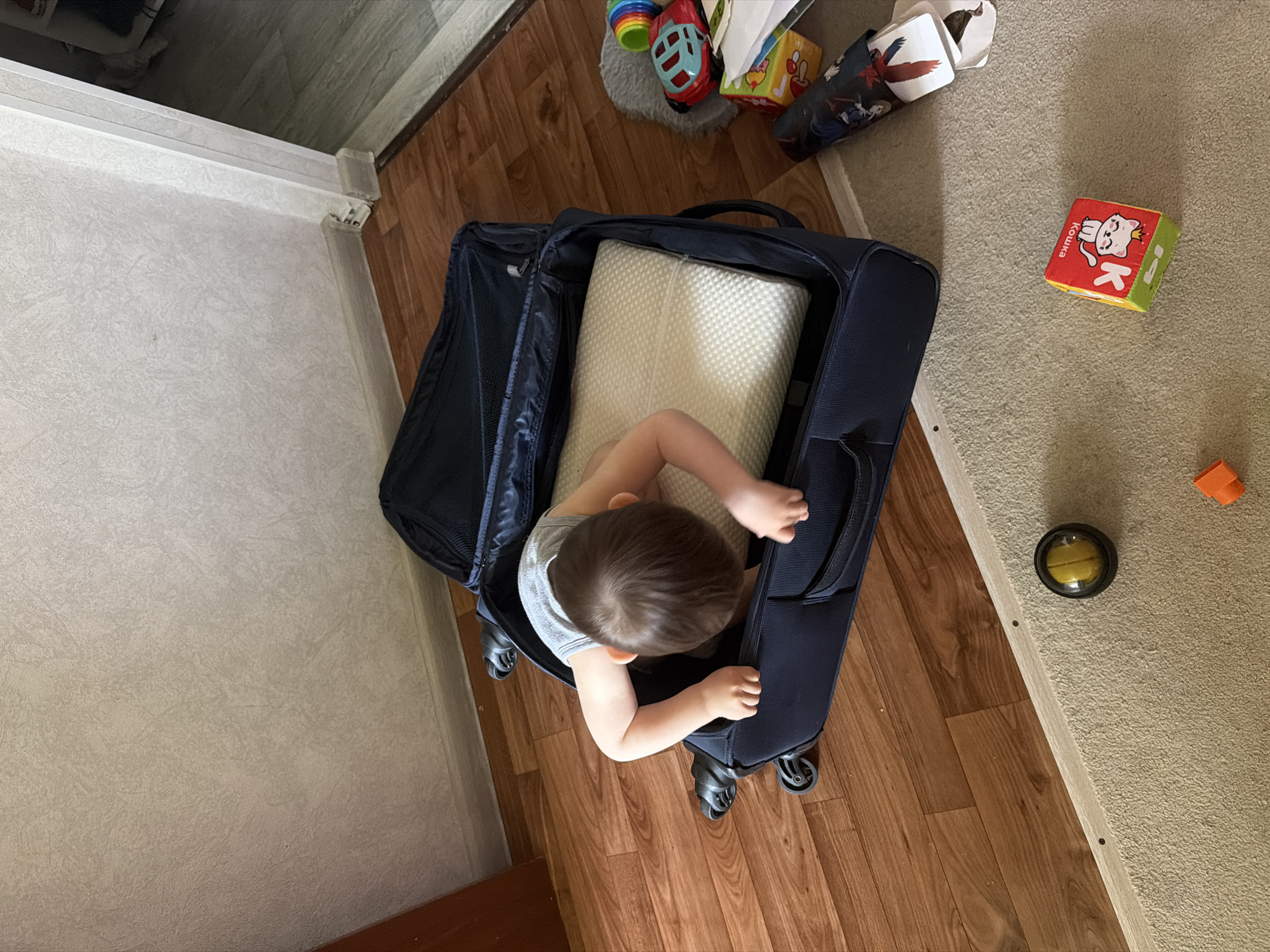 Child sits in suitcase with pillow in Ufa