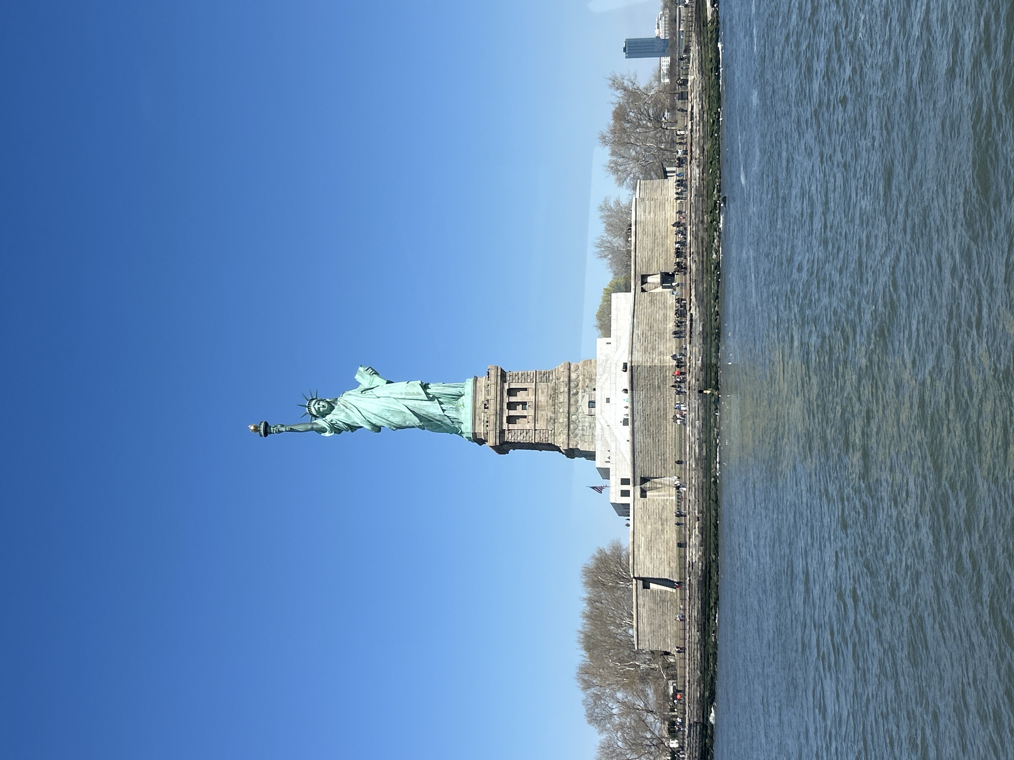 Tourist takes selfie at Statue of Liberty on sunny afternoon