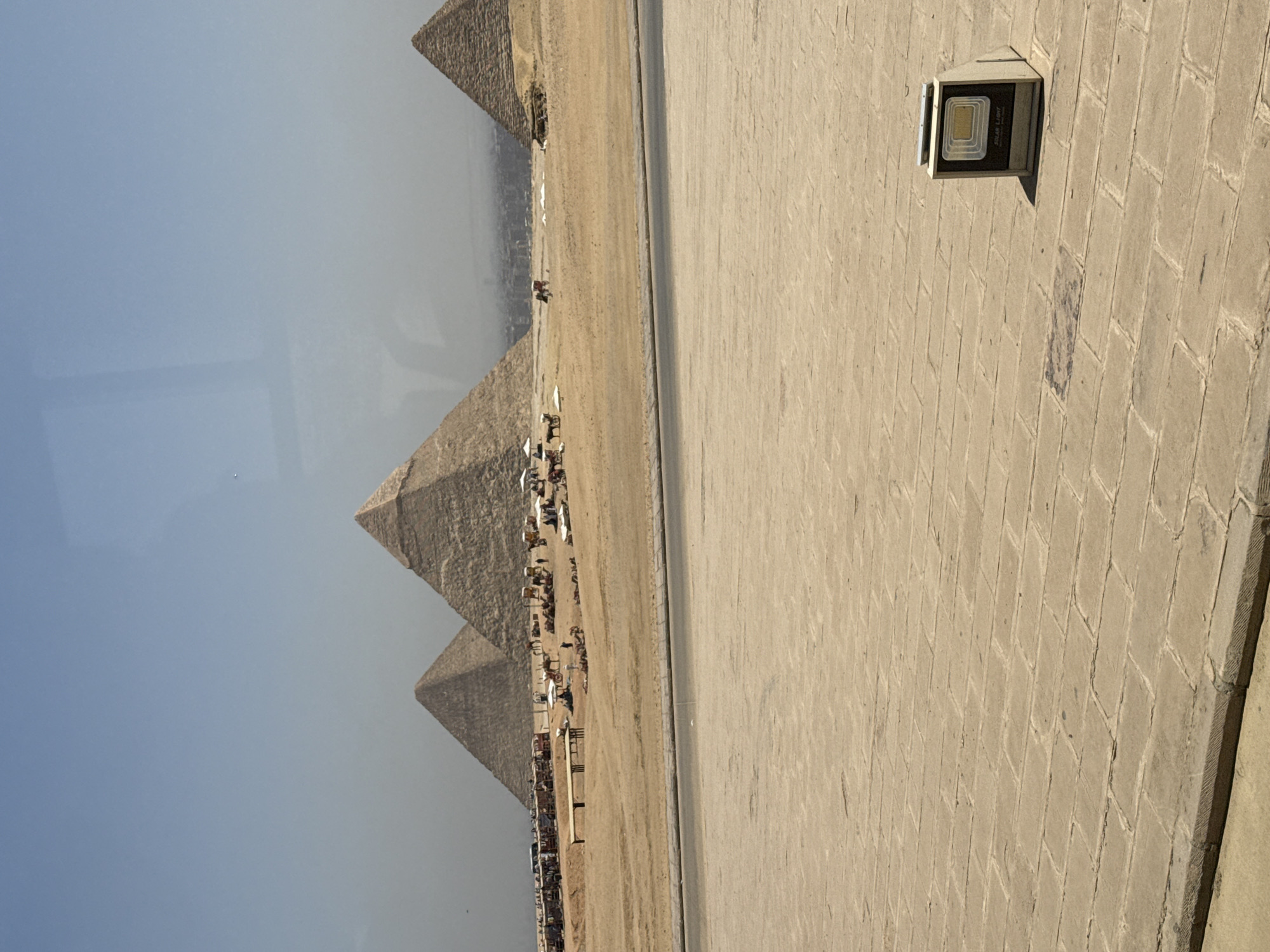 Tourists photograph Giza pyramids on hazy morning