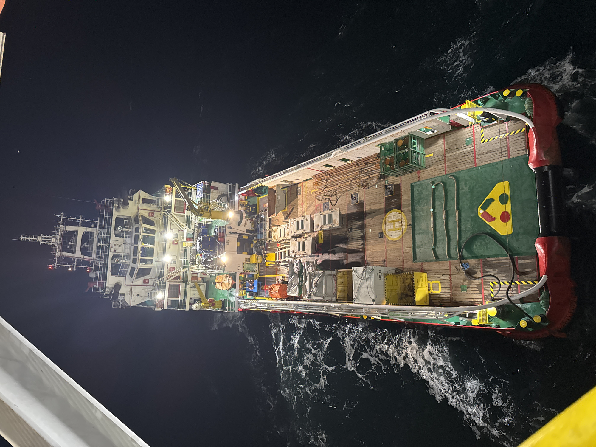 Illuminated cargo ship observed at night off Italian coast