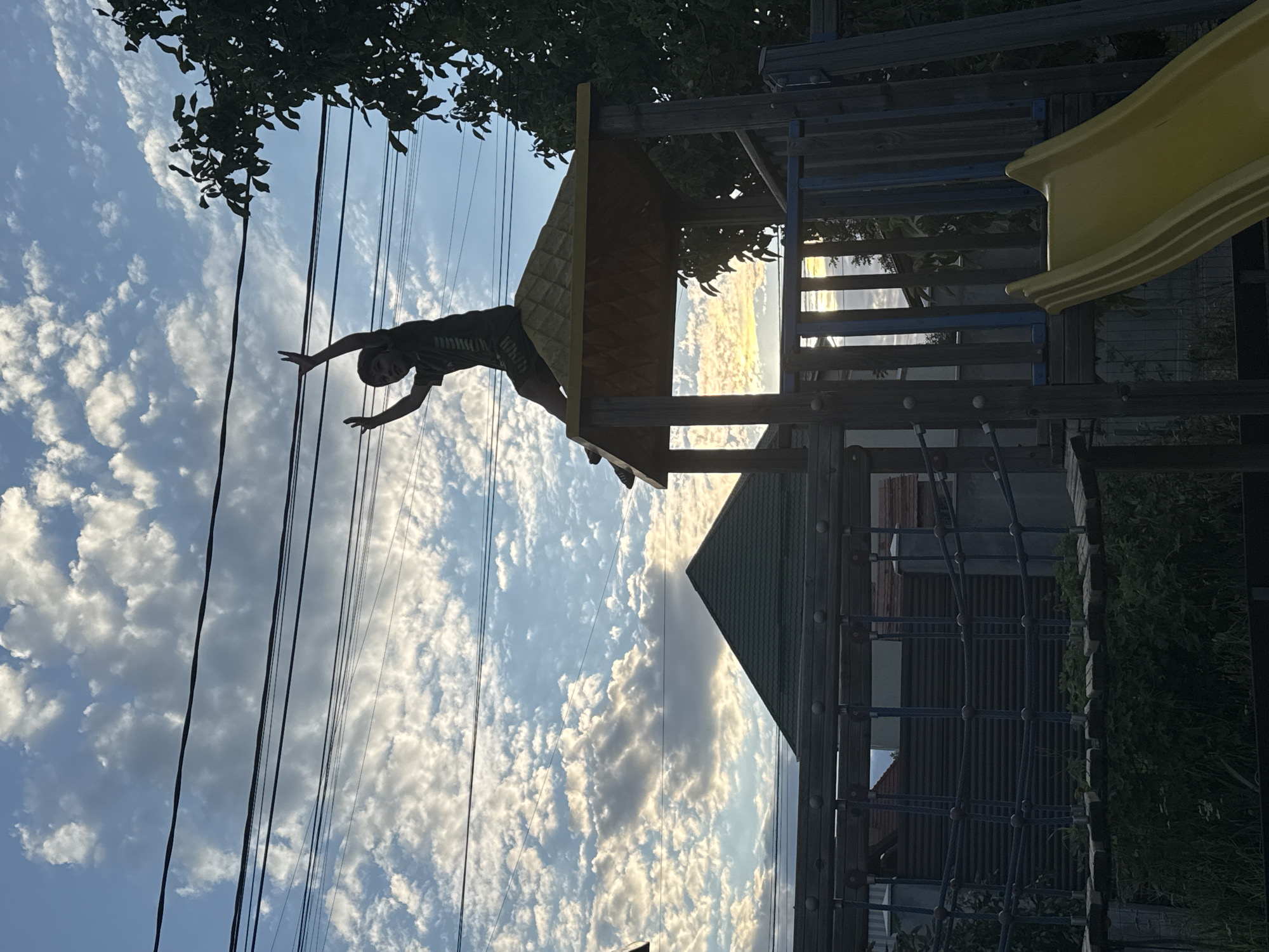 Arms raised atop a playground structure against a Chișinău sunset