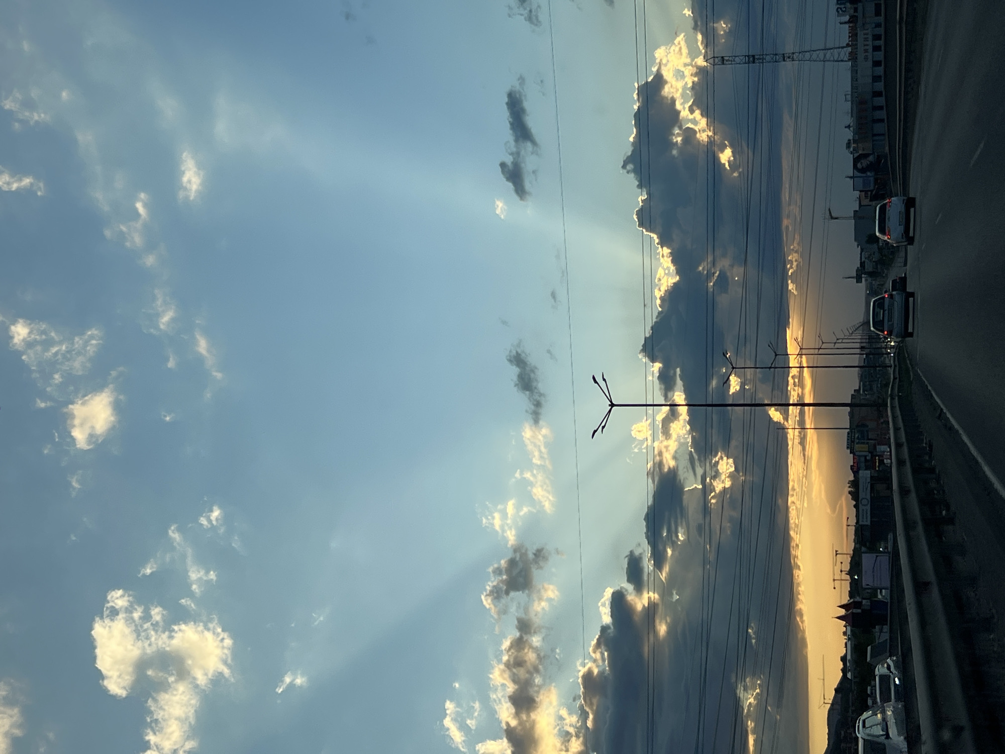 Sunbeams break through clouds over a Sofia highway at sunset.
