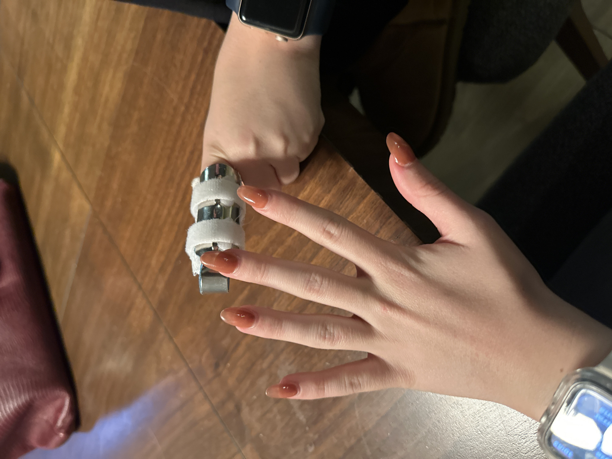 Hands, a finger splint, and a candle on a wooden table