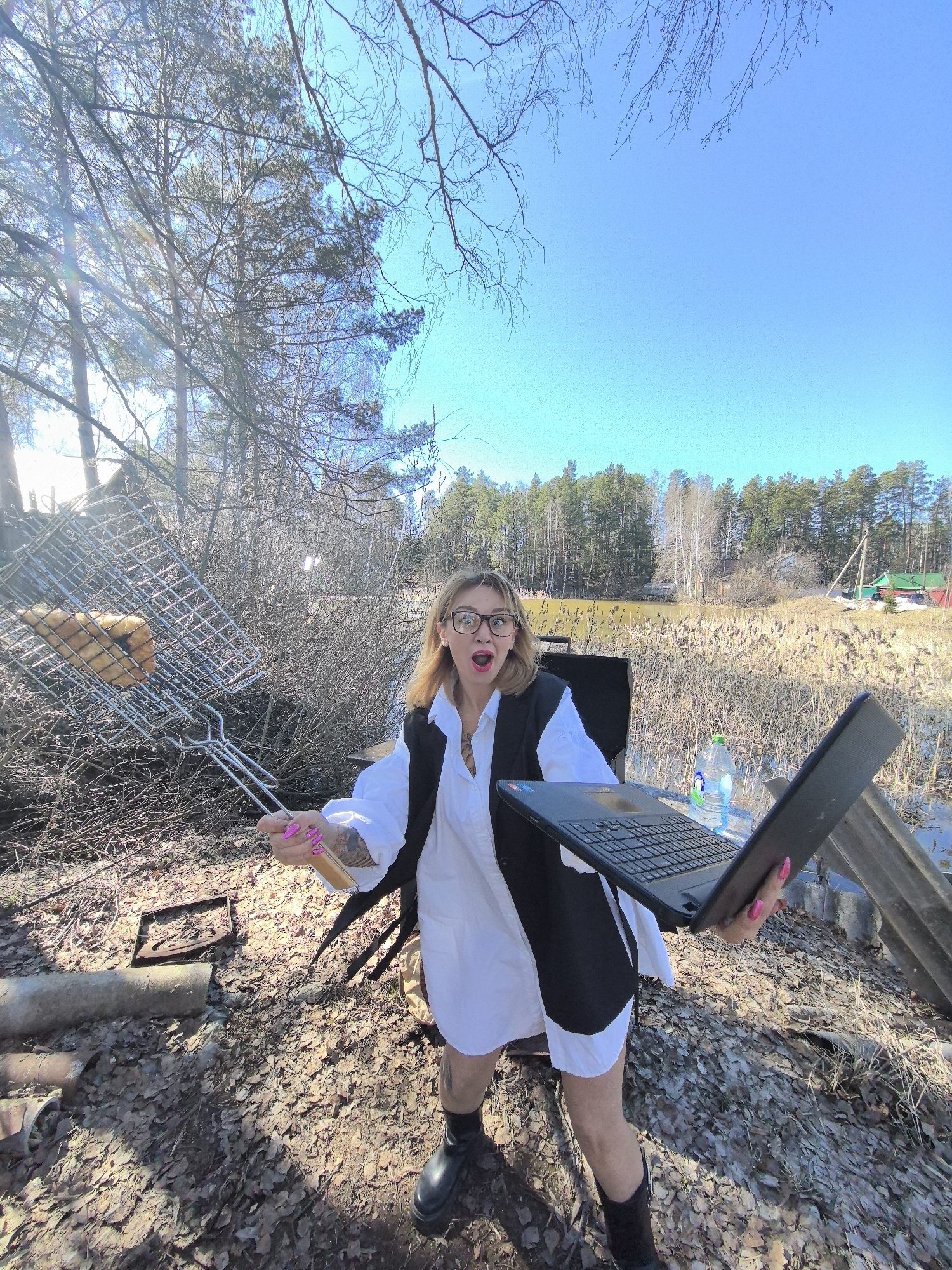 Woman multitasks with laptop while outdoor cooking in Russia