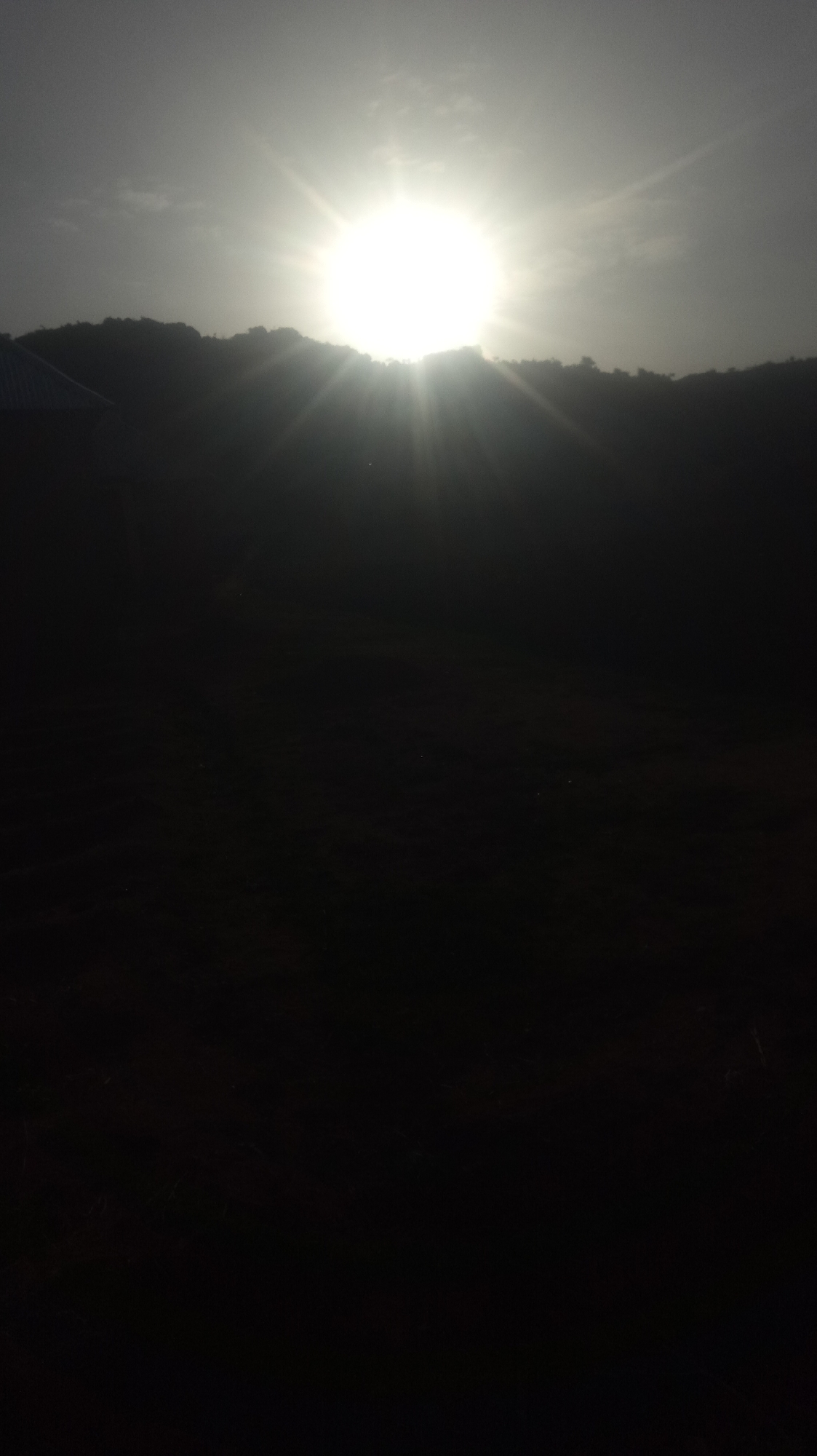 Dawn sunlight captured through silhouetted landscape with building visible