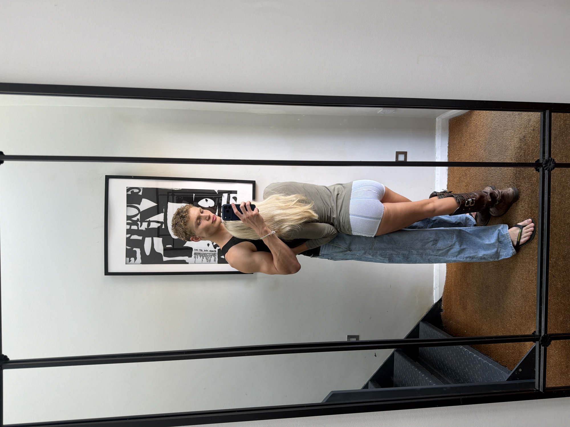 Mirror selfie in a London residential hallway, casual pose.