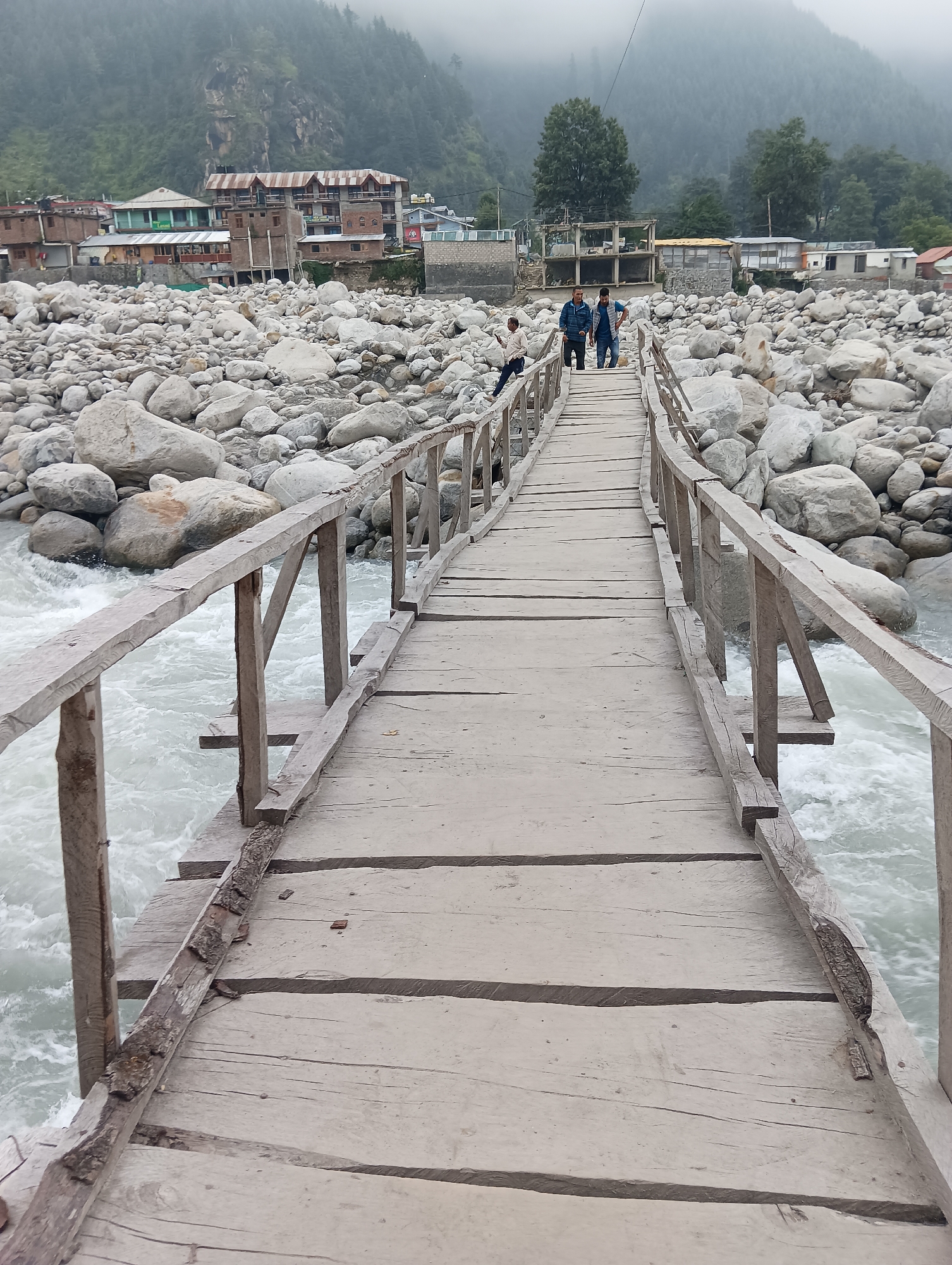 Rough river rapids and a worn footbridge in Bahang