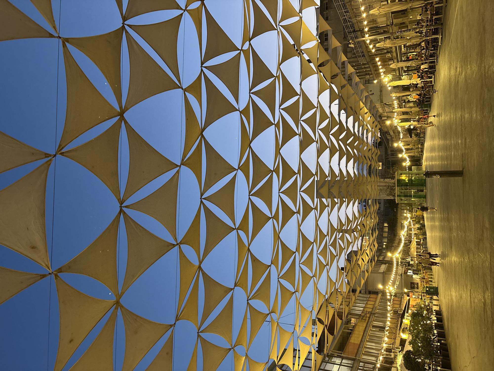 Yellow fabric canopy shades Tel Aviv street at dusk