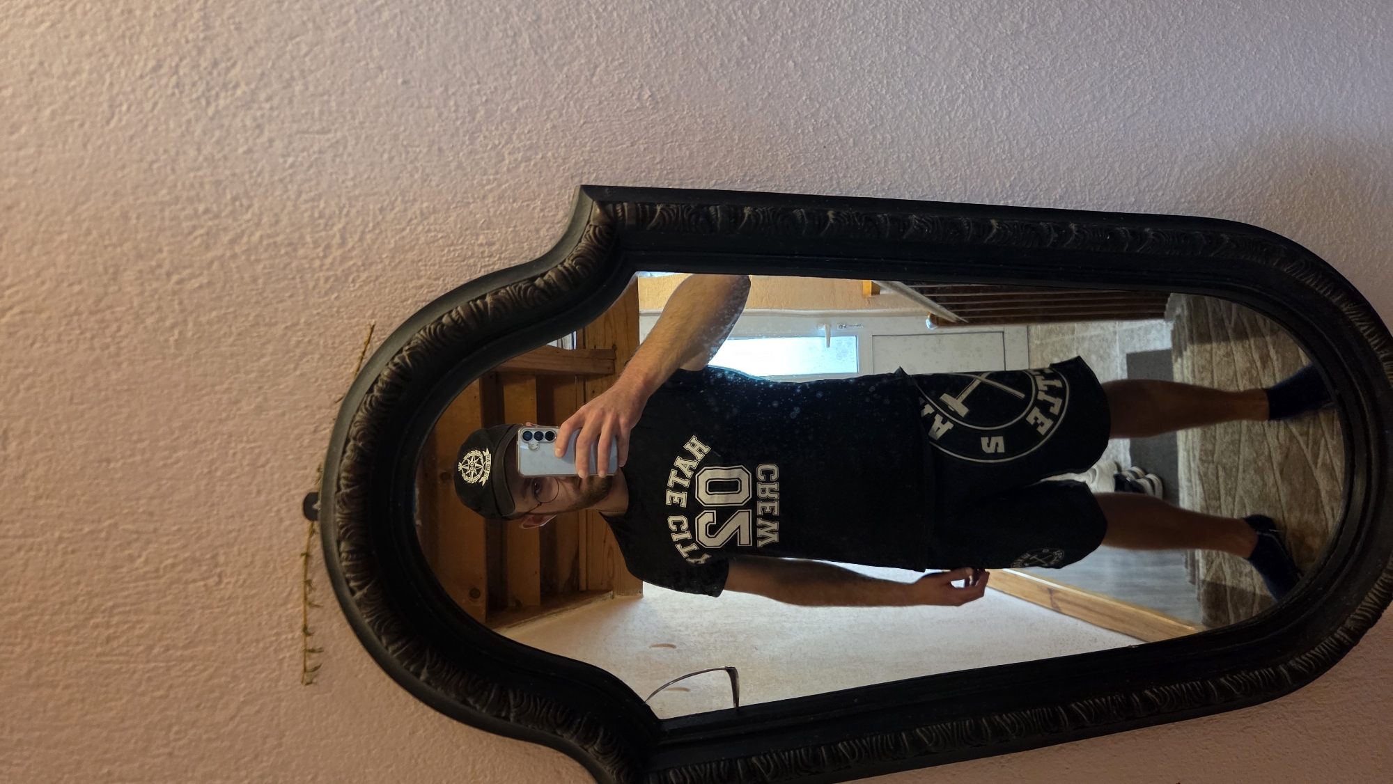 Man takes mirror selfies at home wearing crew t-shirt