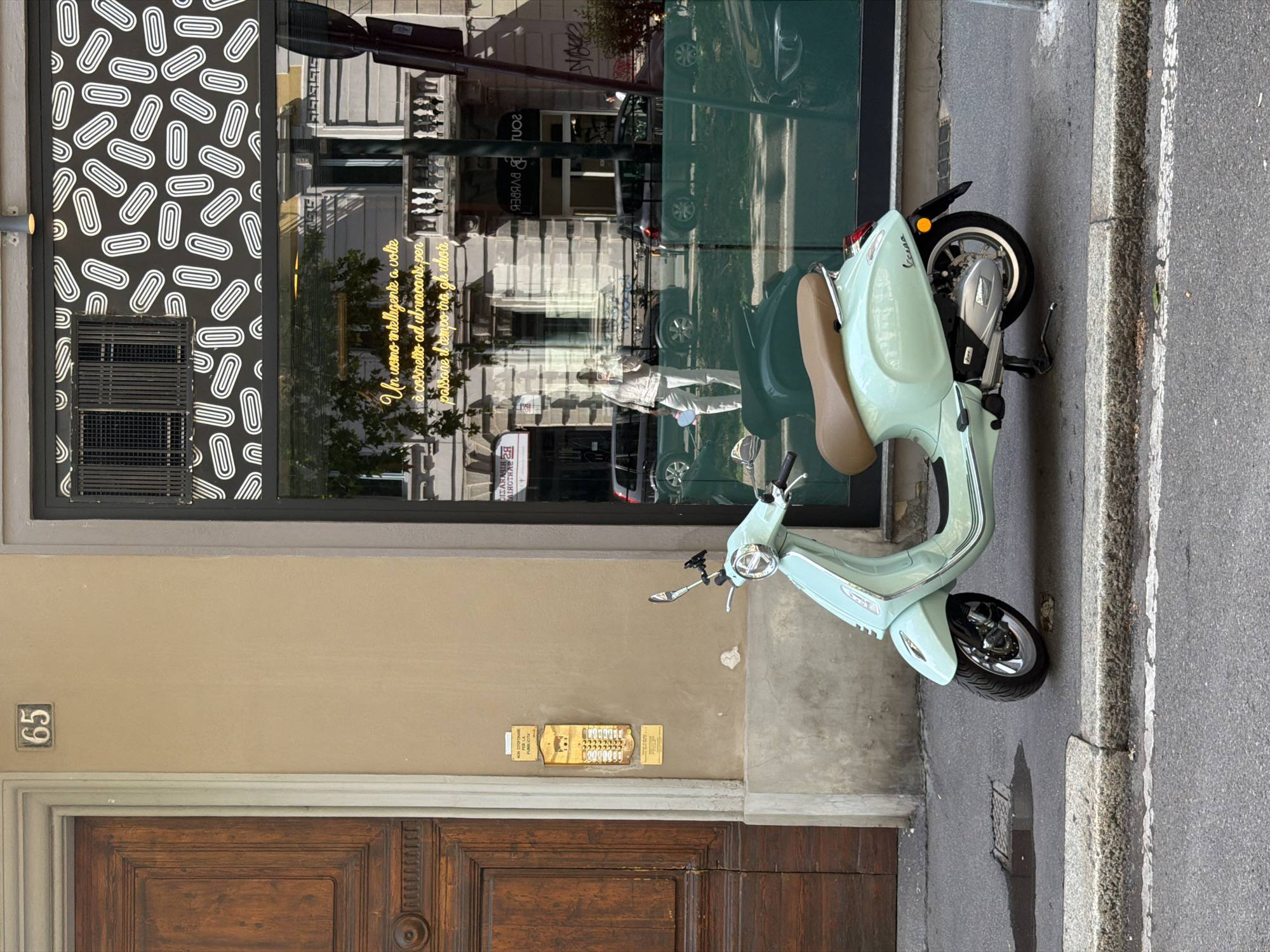 Milan street scene features parked scooter, car near café