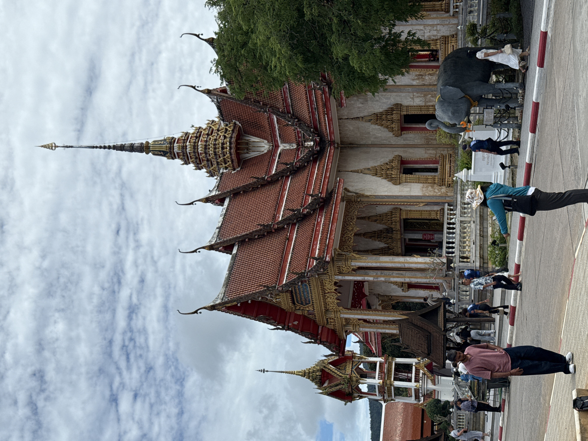 Morning at Wat Chalong — temple grounds, golden spires, a husky in tow