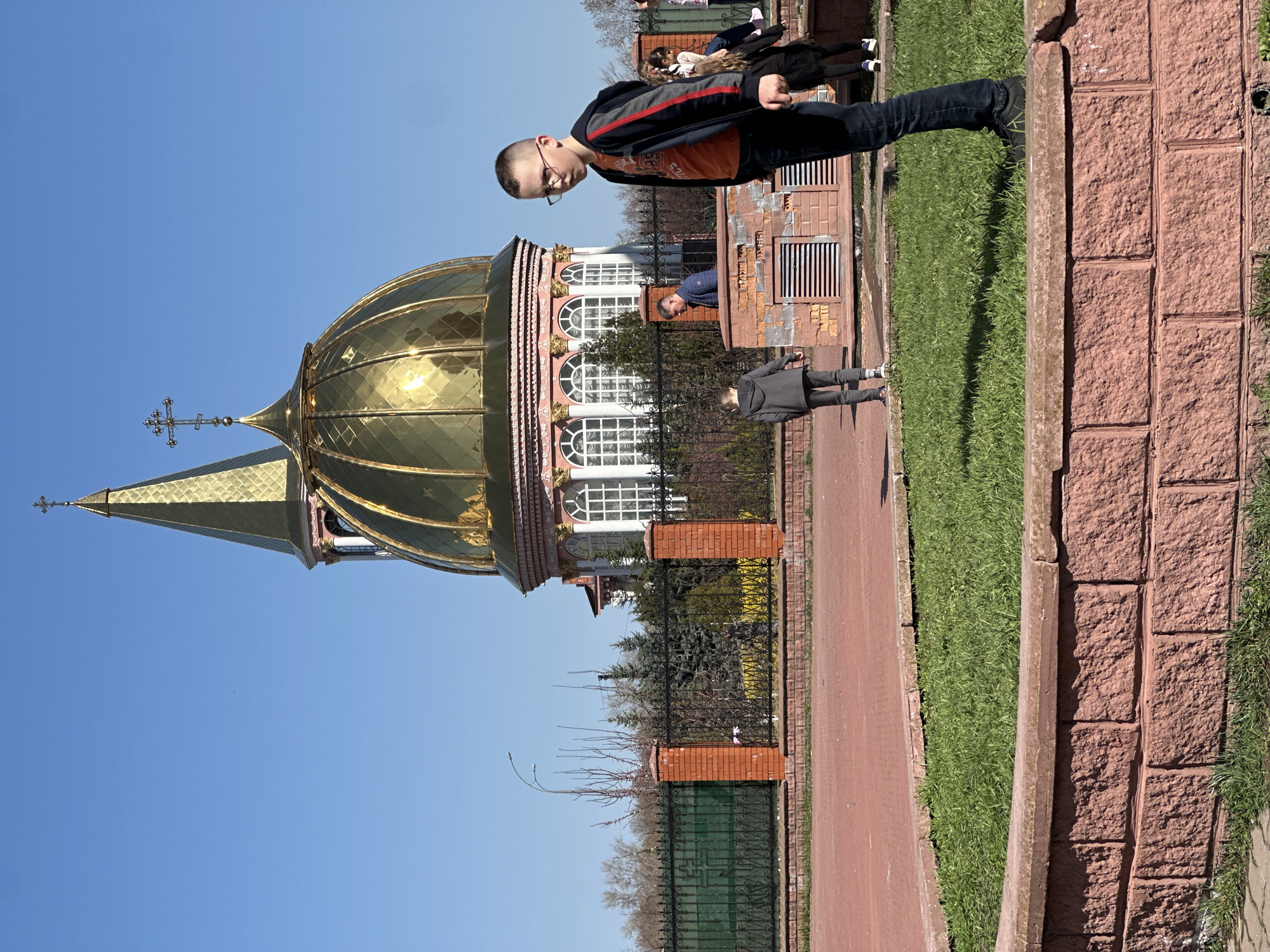 Boy observed near golden-domed church in sunny Kyiv scene
