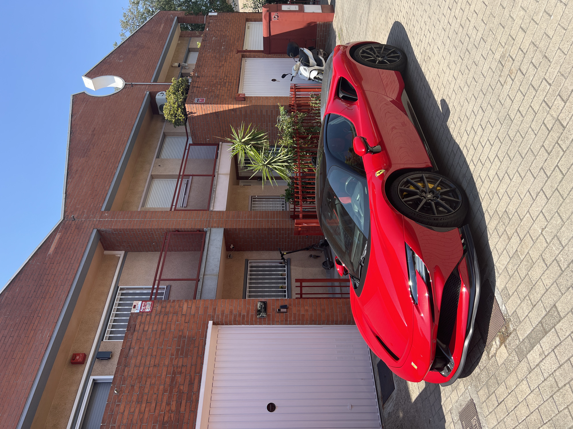 Red Ferrari parked on a brick street in Mollet del Vallès