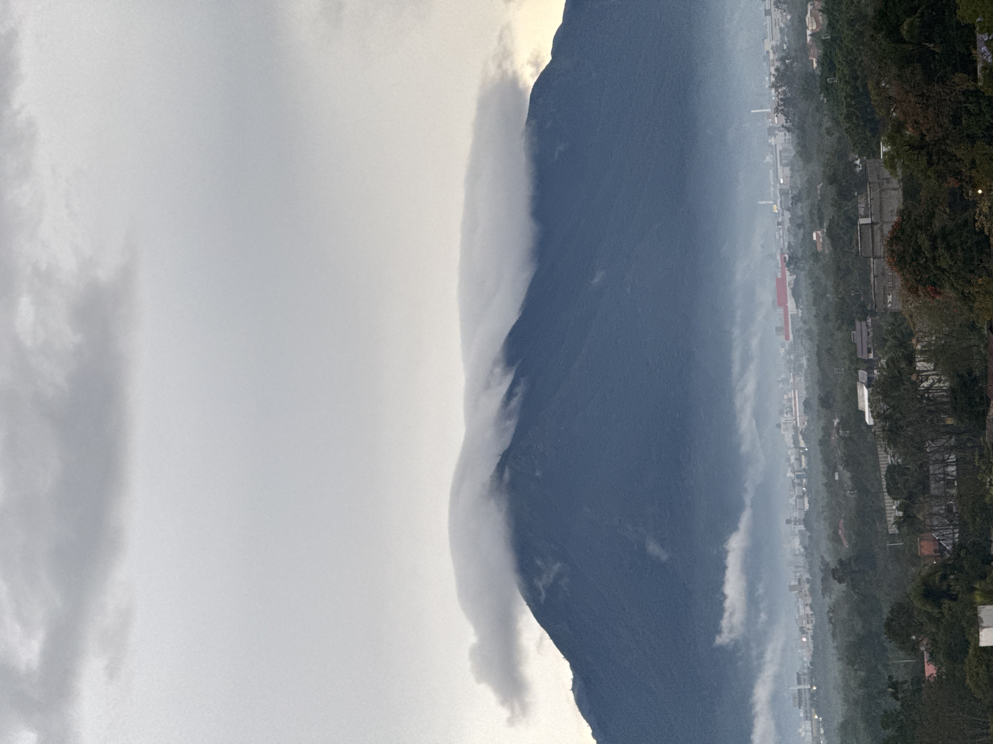 Cloud-draped mountain peak looms over a misty city below