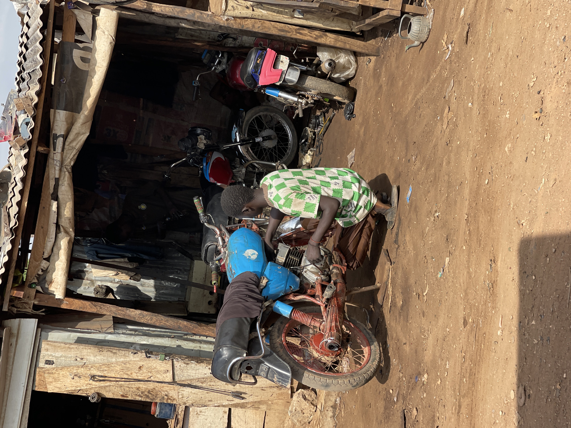 Outdoor metalworking and motorcycle repair operations documented in Abuja