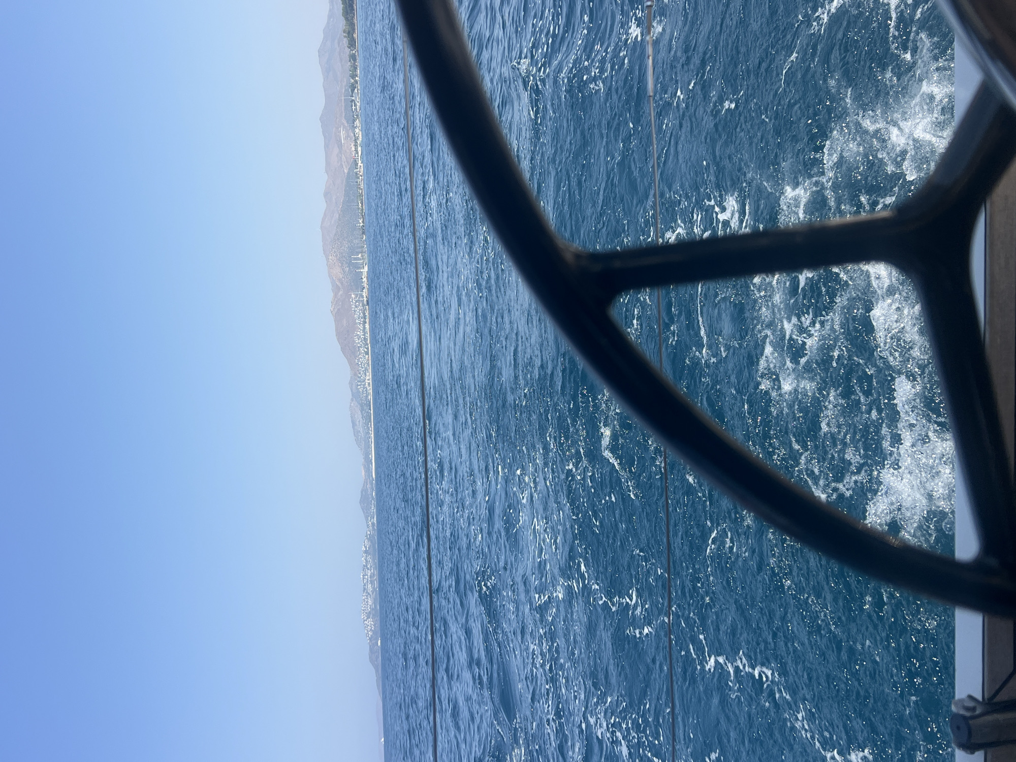 Out on the water, sailing past a sun-drenched coastal town.