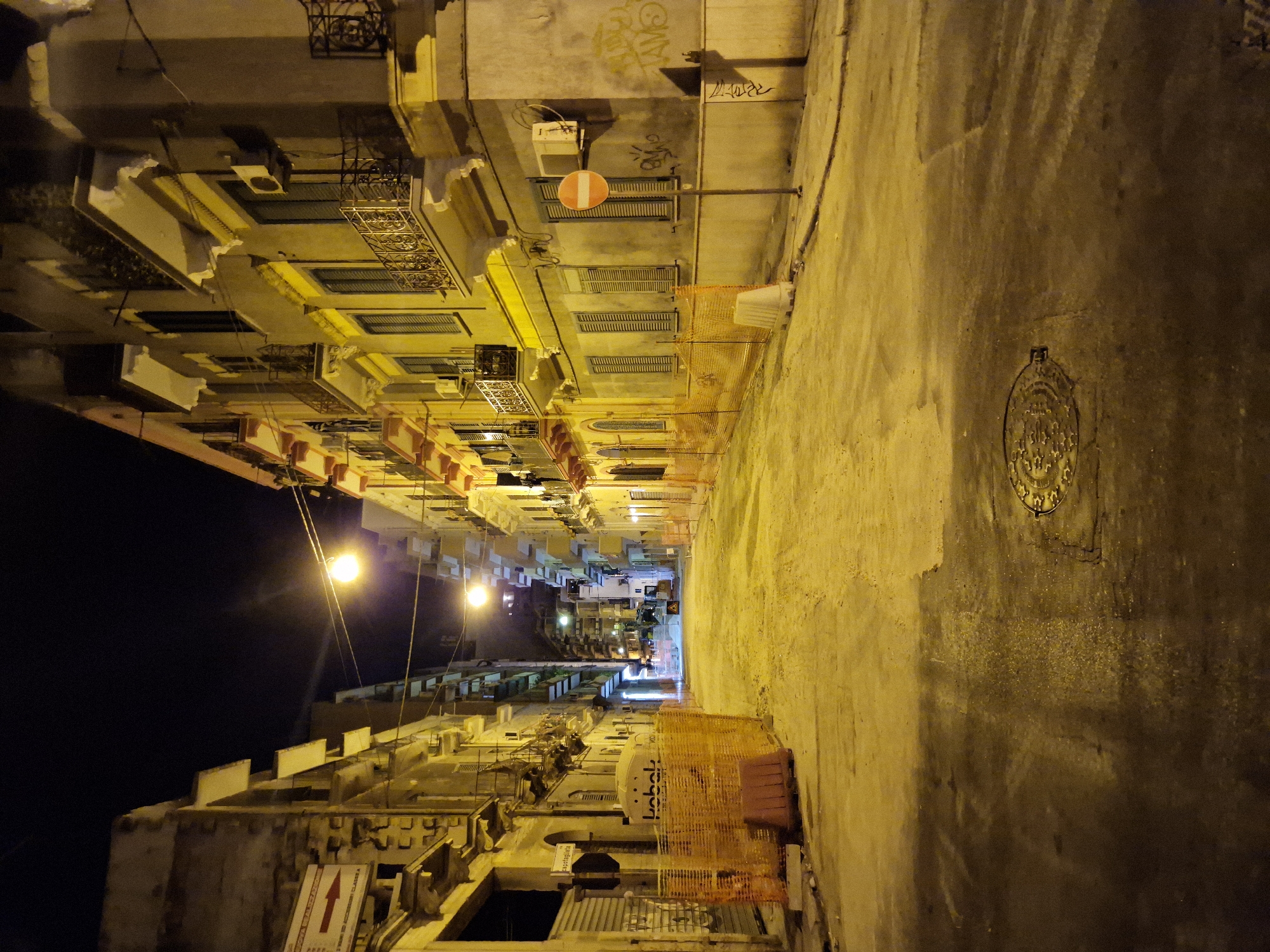 Nighttime streets of Taranto, old stone walls and parked cars