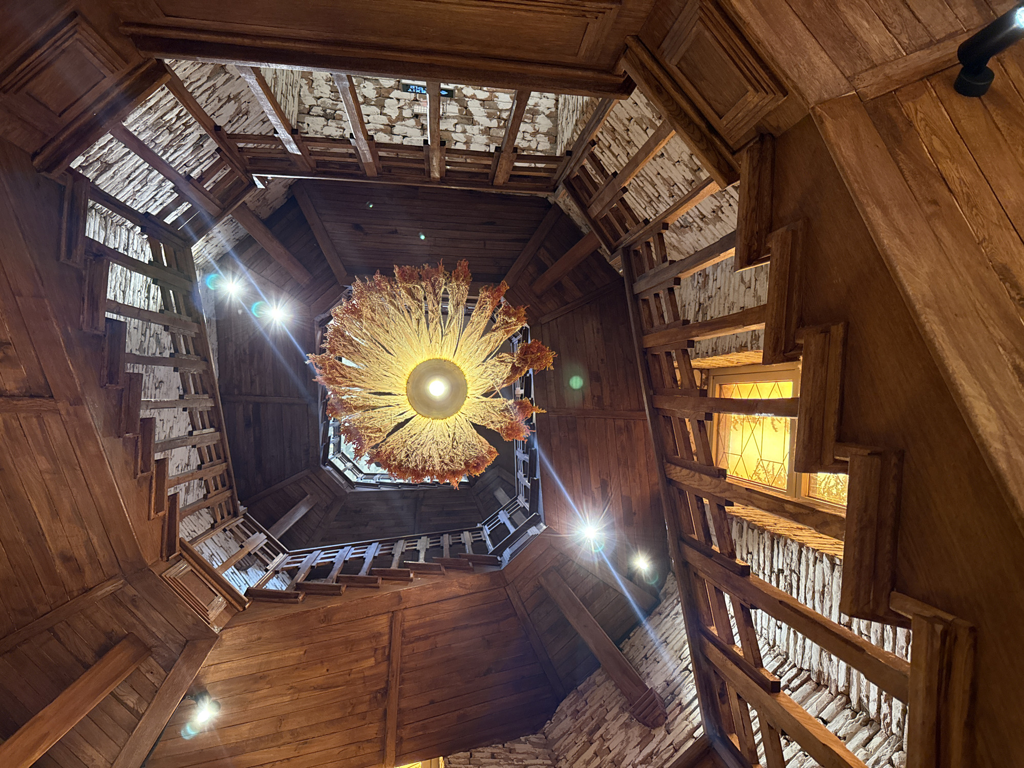 Low-angle views of a rustic wooden spiral staircase and brick facade