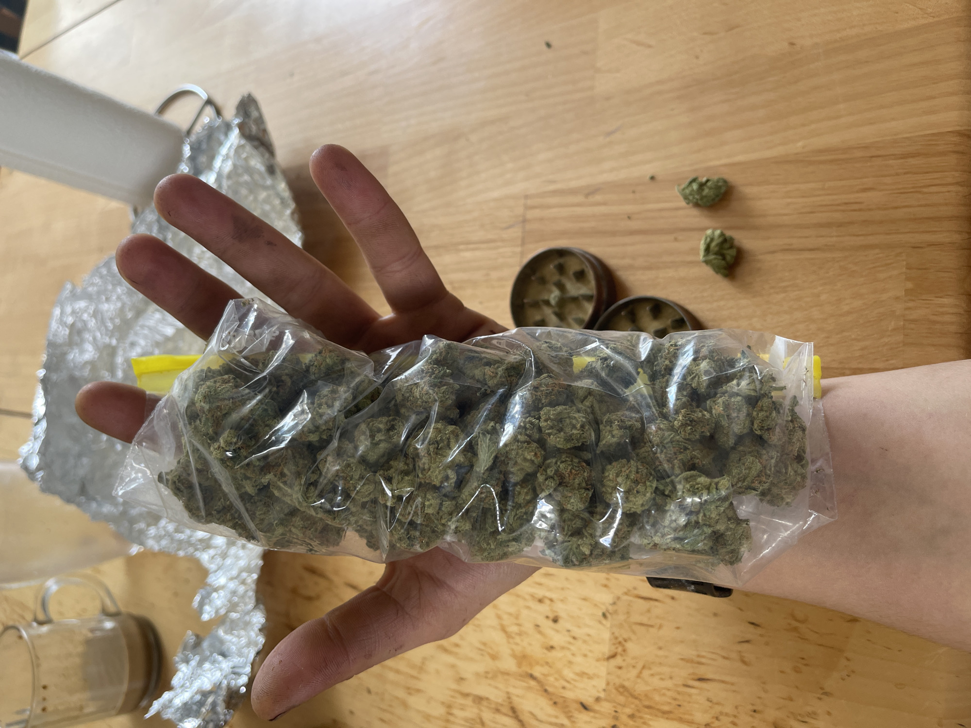 Individual observed preparing cannabis materials with various paraphernalia indoors