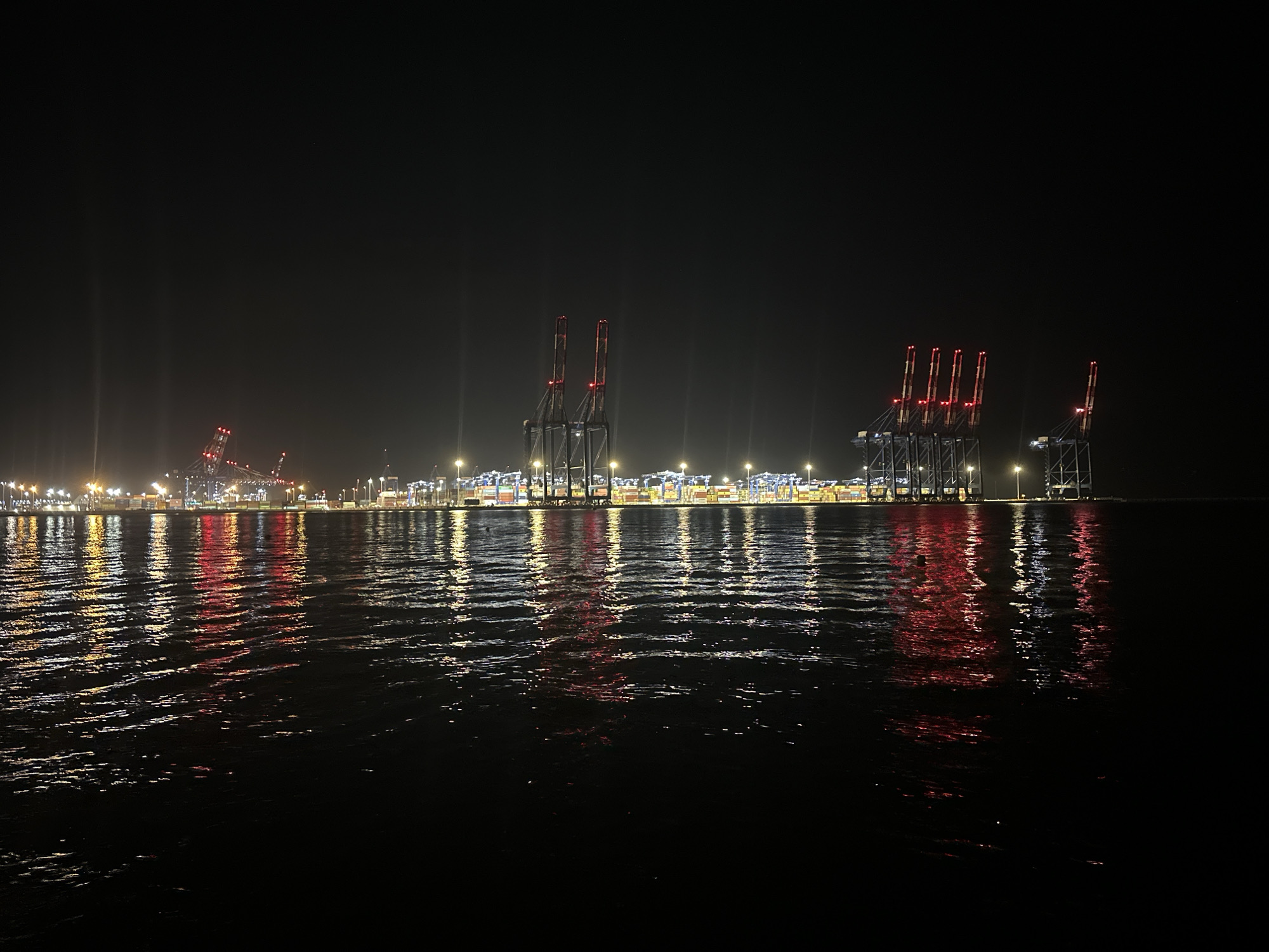 Gdańsk container terminal glows at night, viewed from the water