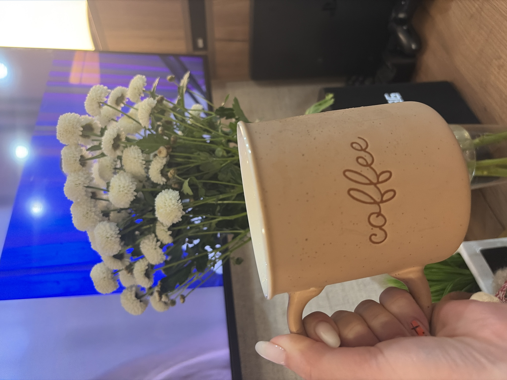 Person holds flowers and coffee mug in Chaikovsky, Russia
