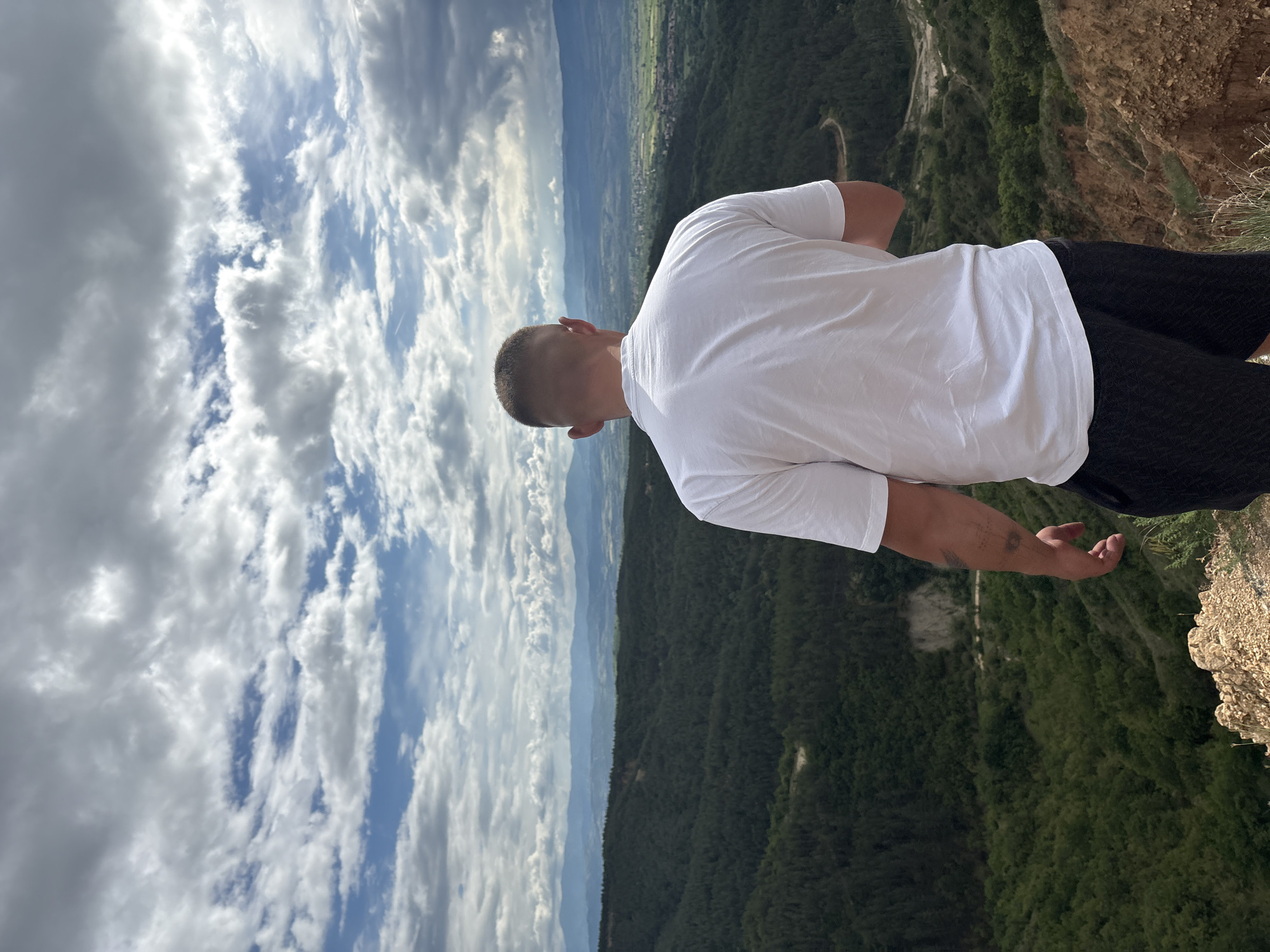 Man stands at cliff edge overlooking valley in Porominovo