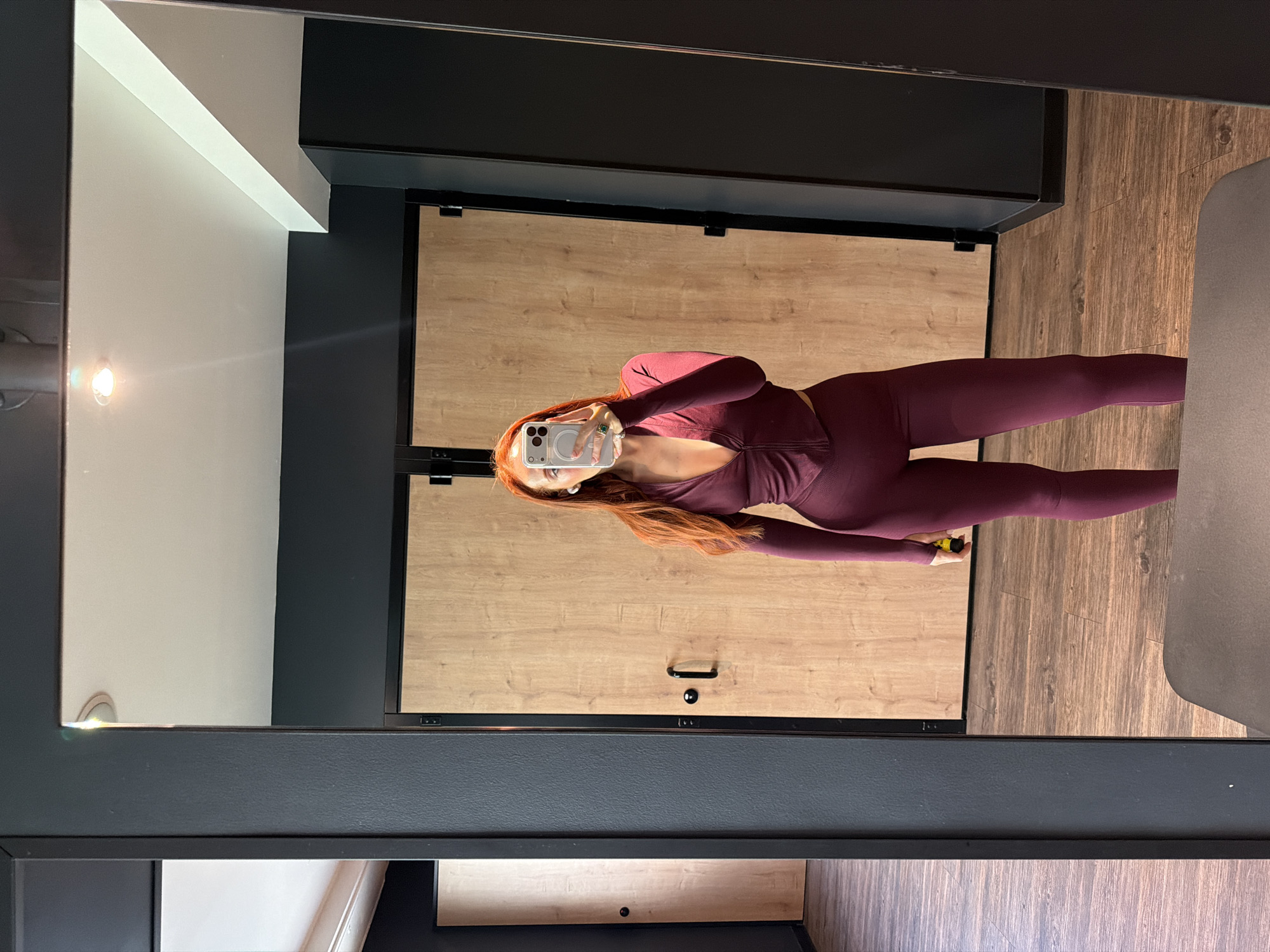 Woman takes mirror selfie in activewear in Paris room