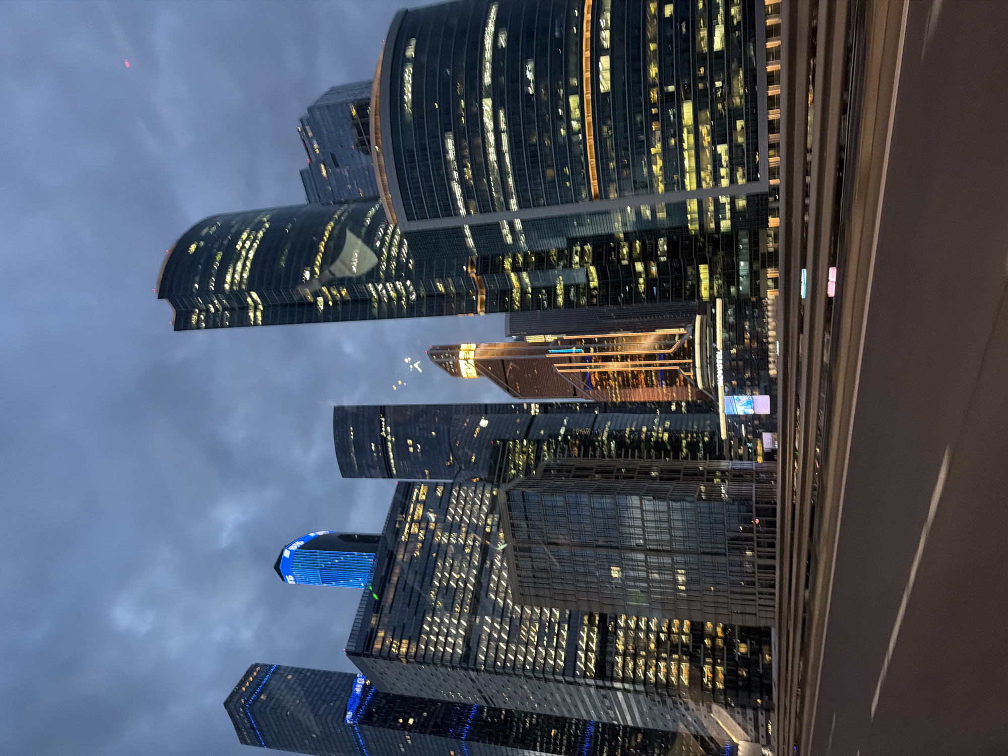 City skyscrapers glow against a dark cloudy night sky.