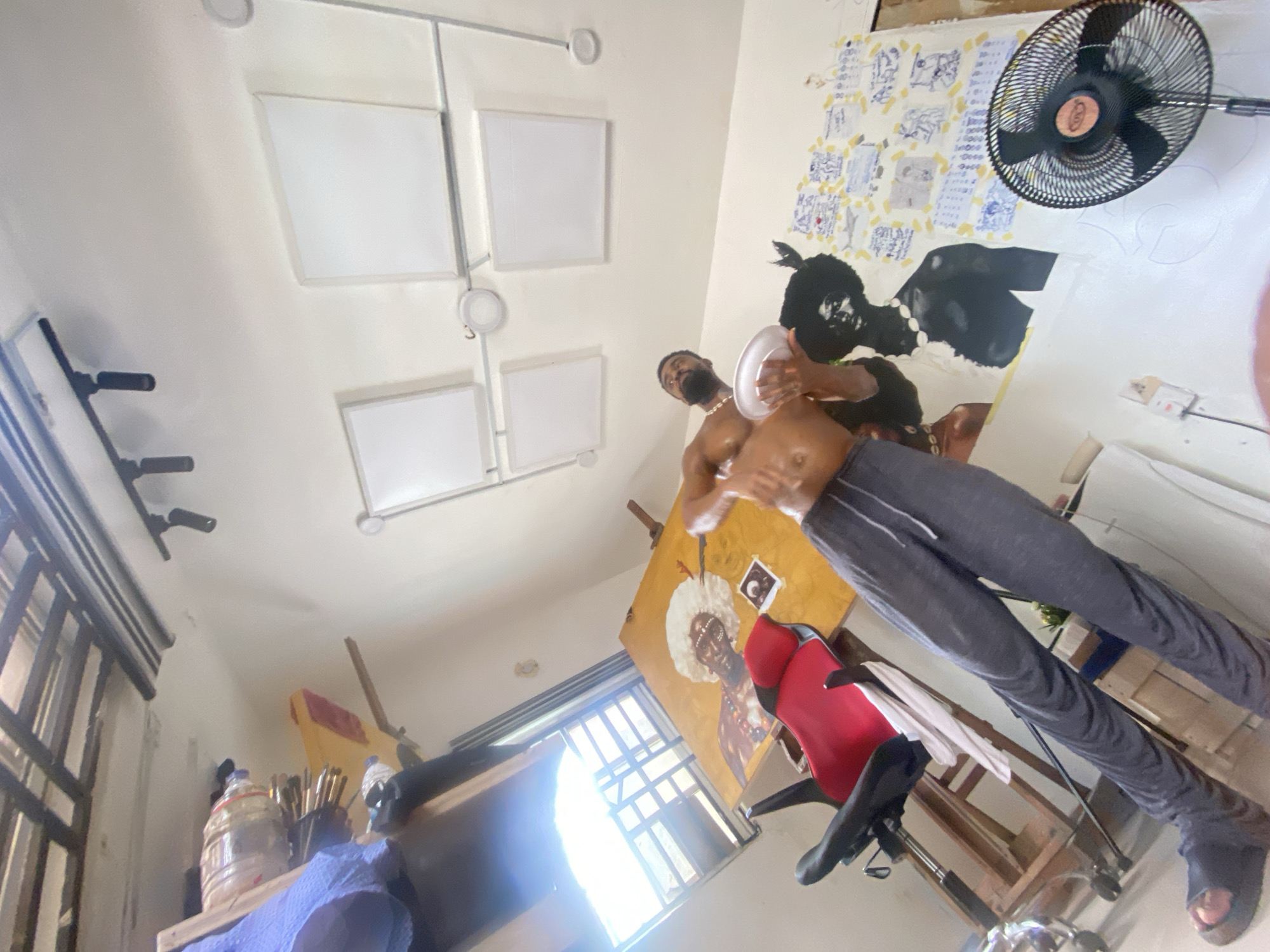Artist documented working in studio with portrait painting in Ado