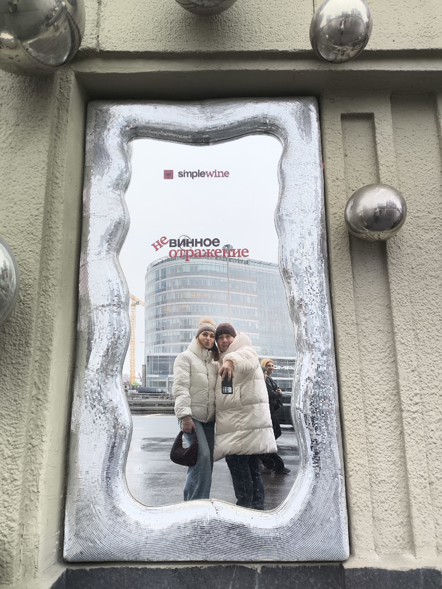 Two women photograph themselves in decorative mirror in Moscow