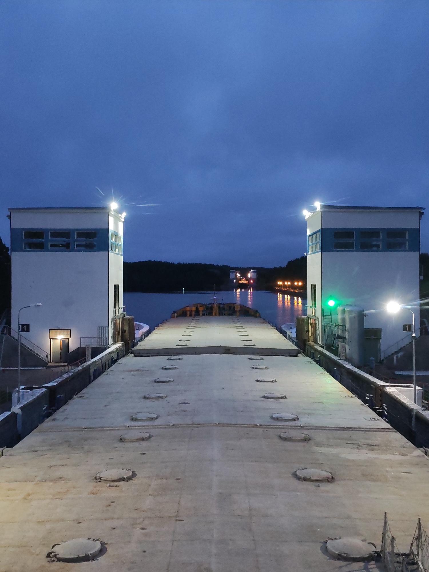 Ship navigates Markovo canal lock at dusk