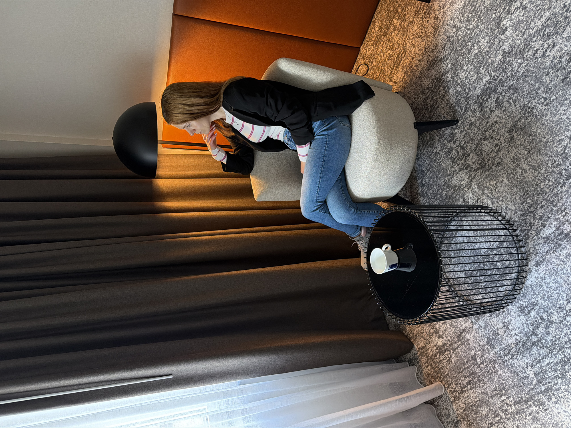 Woman sits in chair with coffee in Düsseldorf room