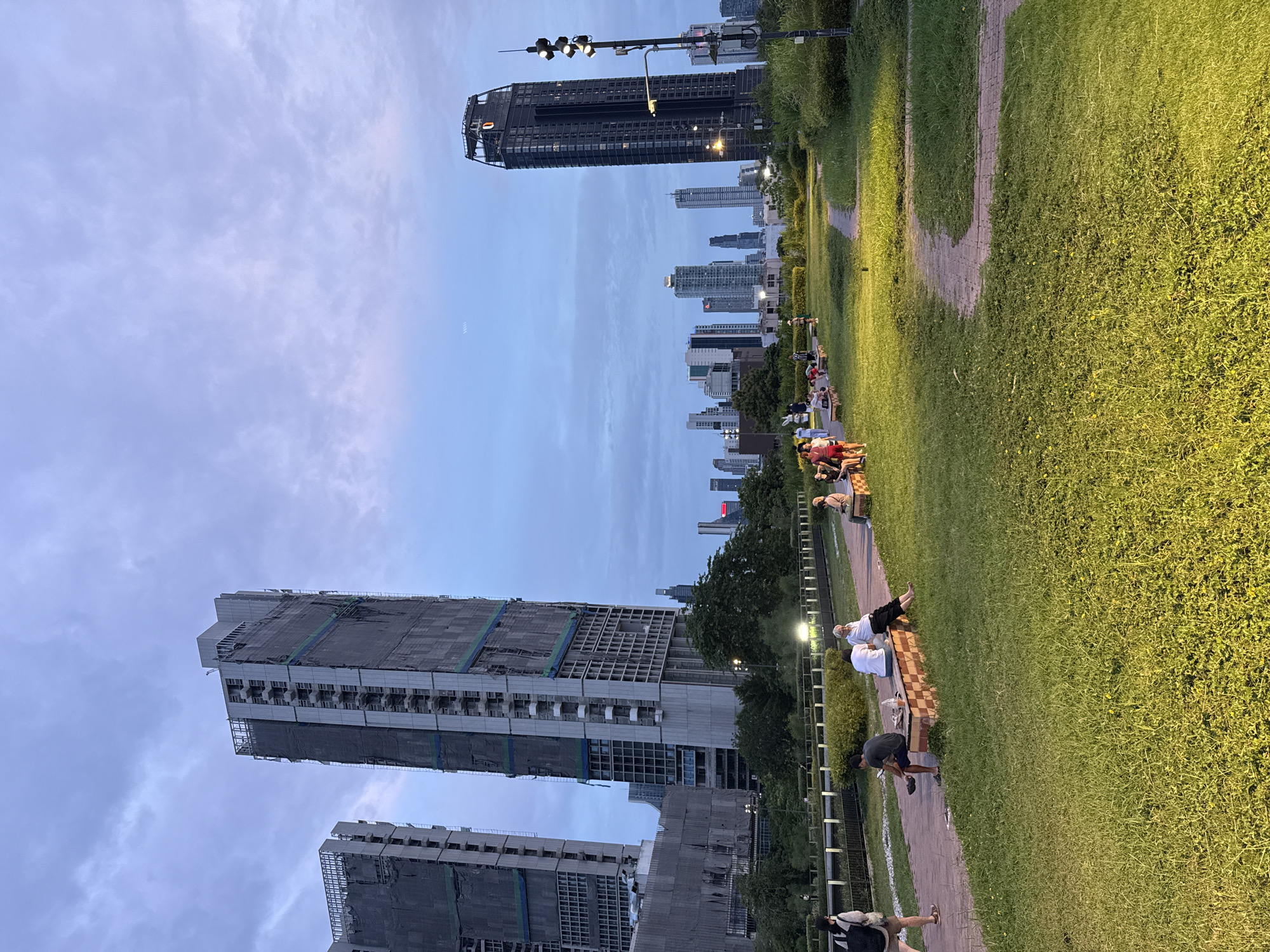Lumphini Park at dusk, city skyline looming behind the green