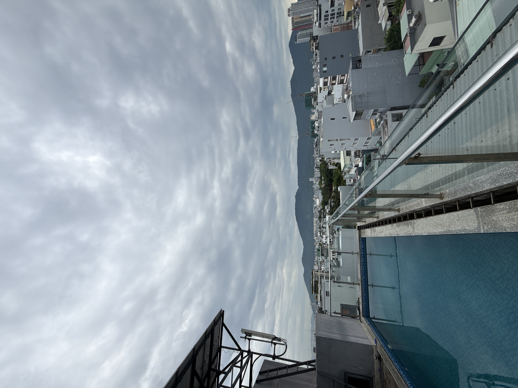 Tattooed visitor documents rooftop pool experience in Đà Nẵng cityscape