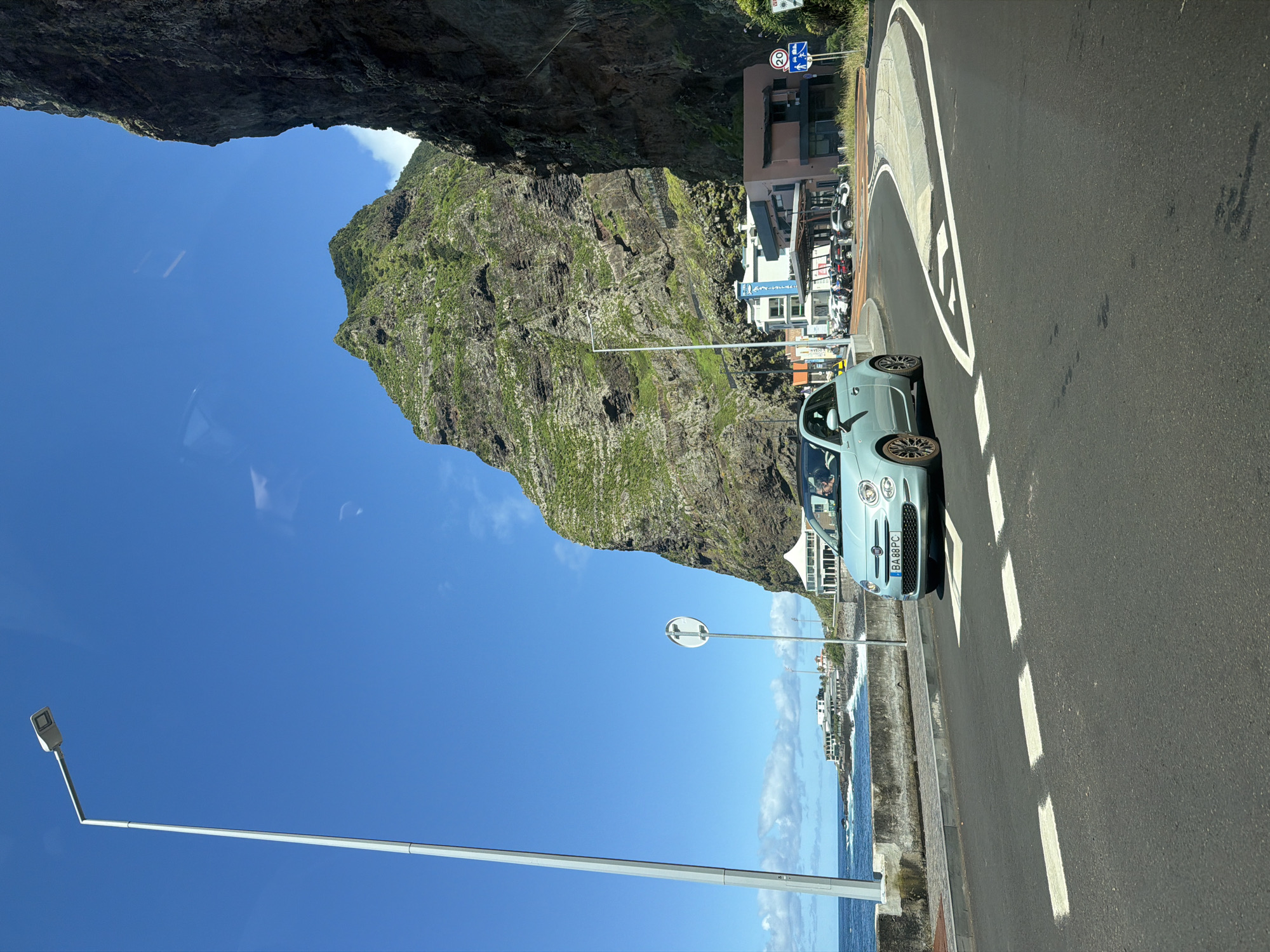 Blue Fiat turns on coastal road near São Vicente mountain