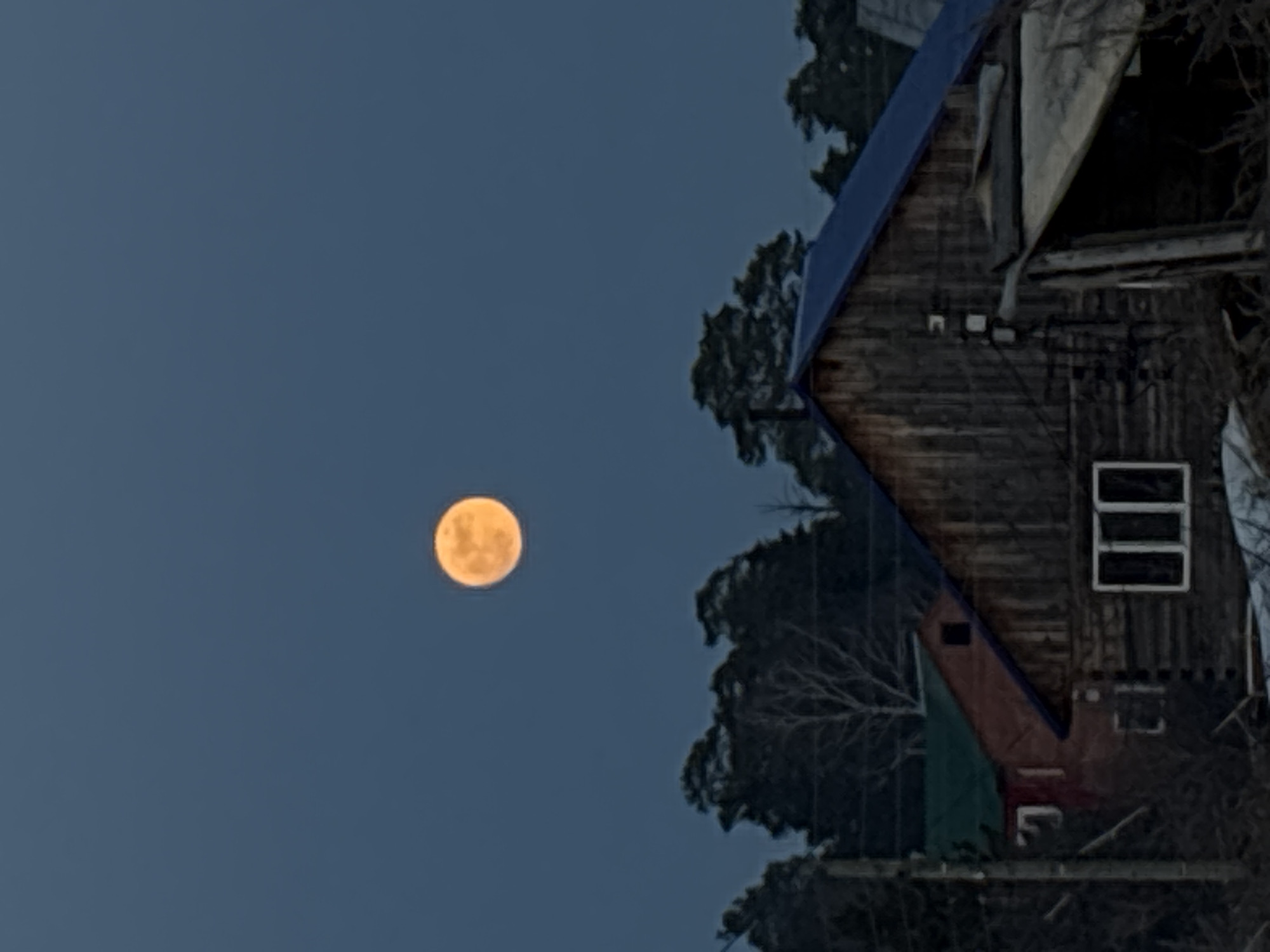 Full moon rises over wooden house in Chaikovsky