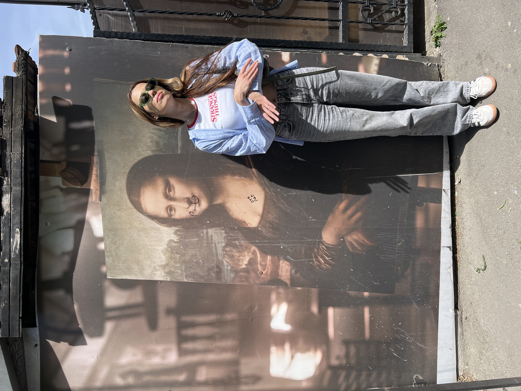 Woman lies on damaged Mona Lisa advertisement in Belgrade suburb
