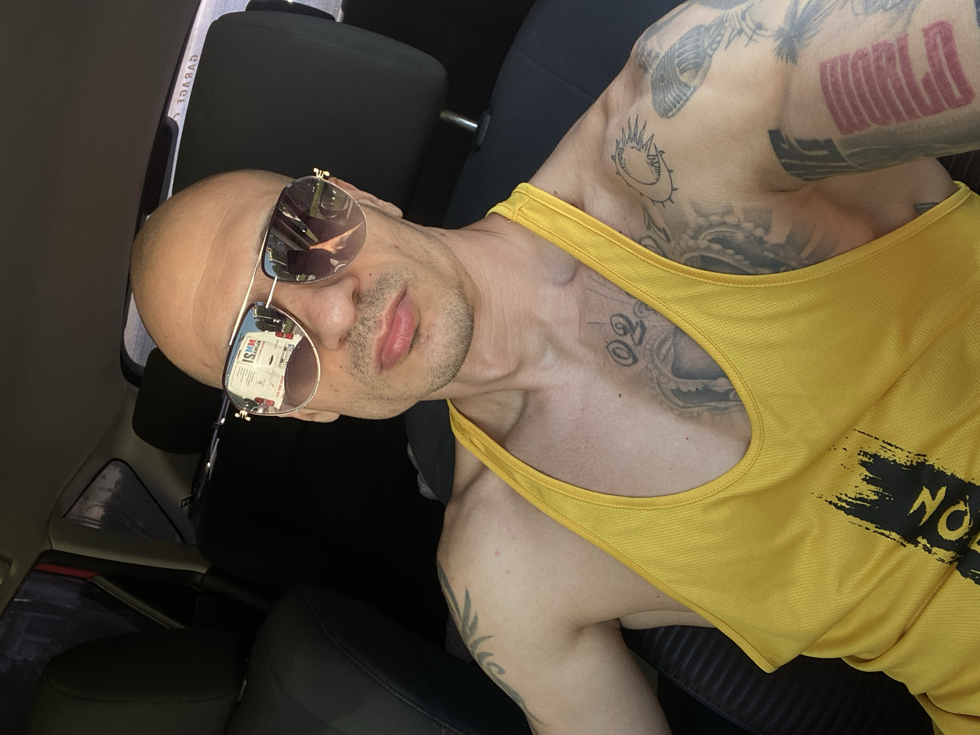 Man in sunglasses, yellow tank top spotted in car