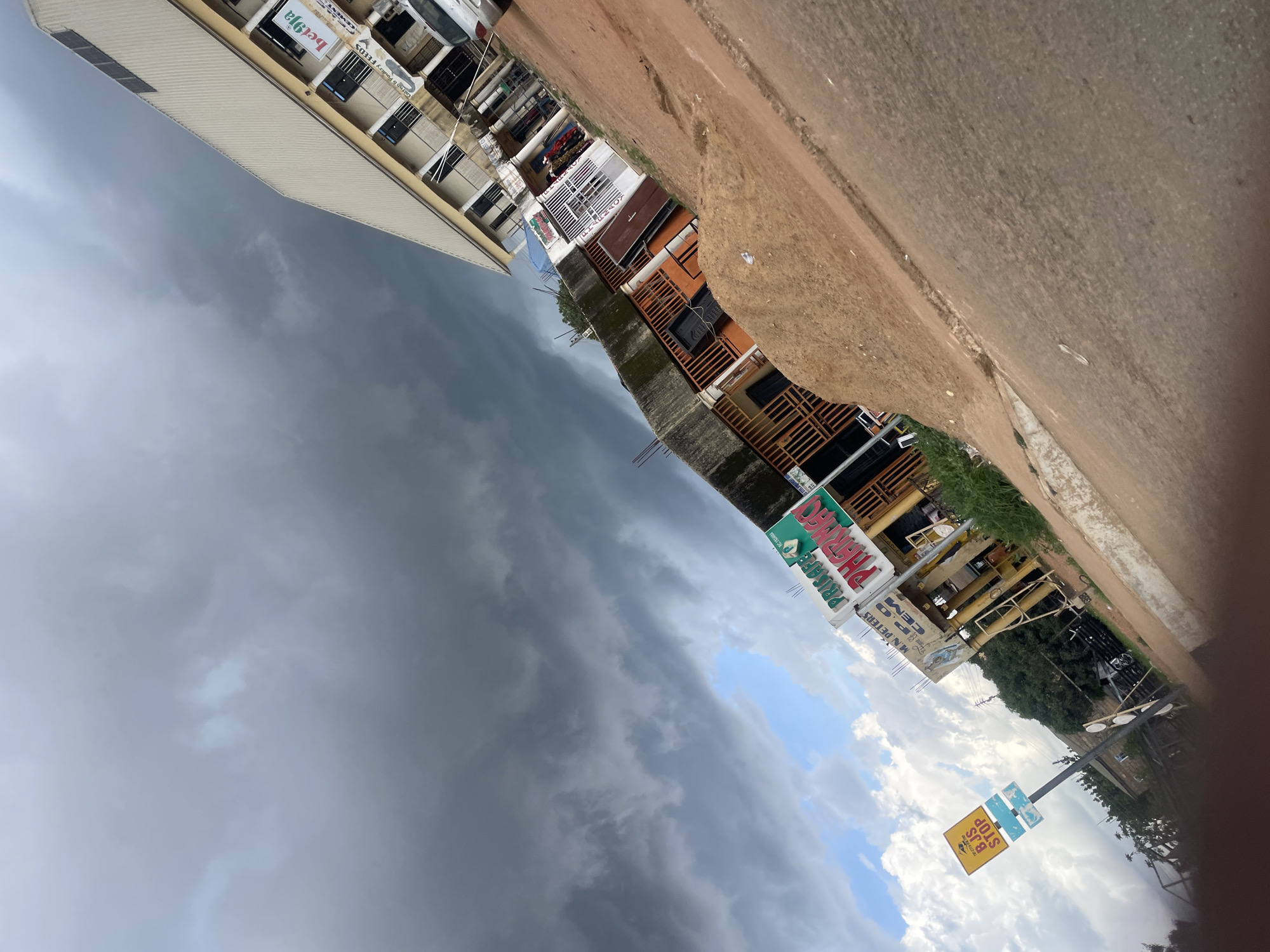Stormy skies over Gura Top streets, goats and signage in Jos