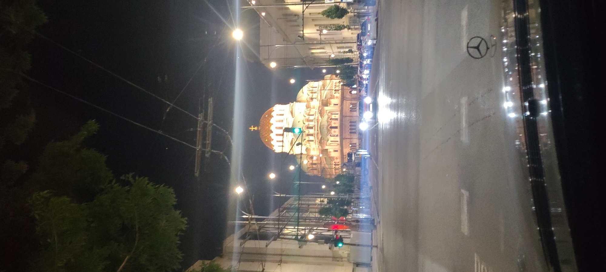 Nighttime scenes capture illuminated domed building amid city traffic