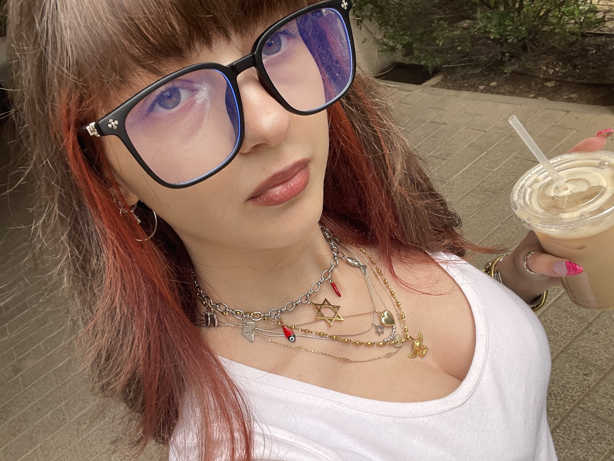Woman takes selfies with drink in Raanana elevator, outdoors