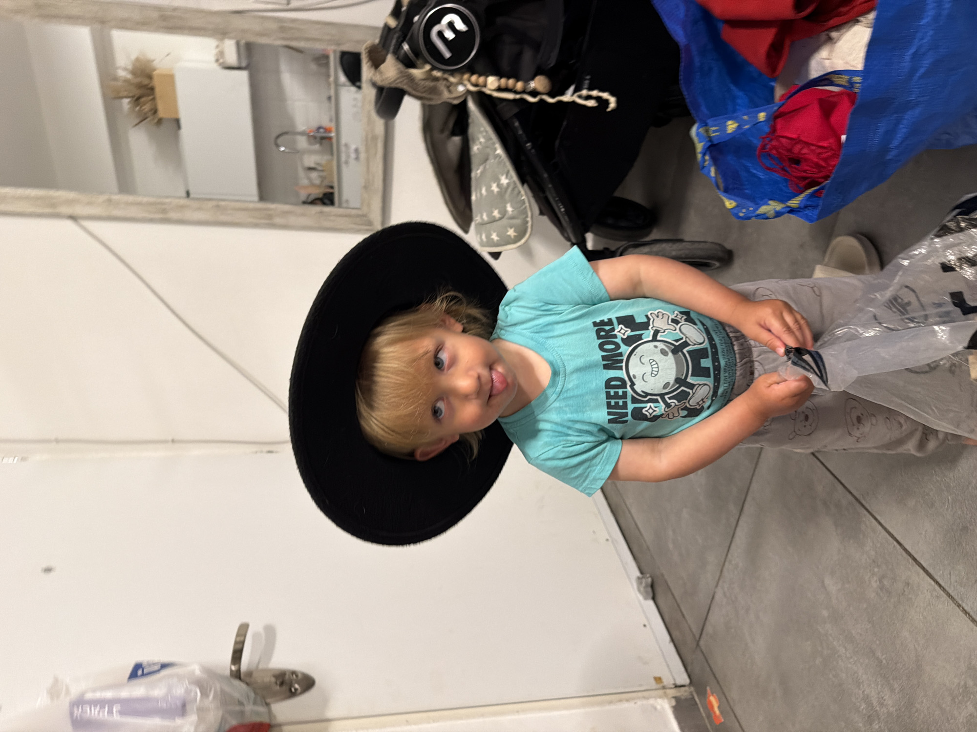 Child in oversized black hat spotted indoors in Bat Yam