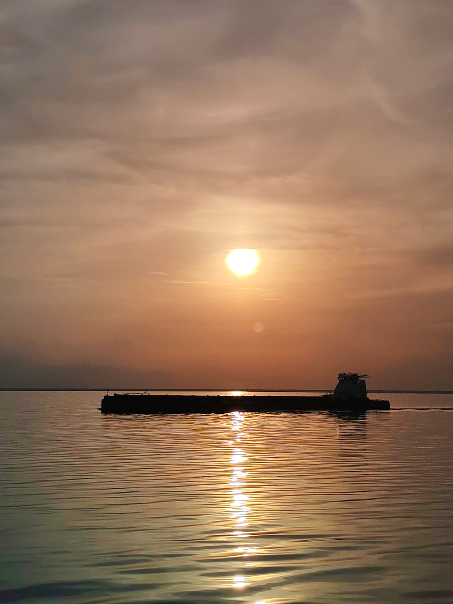 Cargo barge silhouetted against orange sky in Belozersk waters