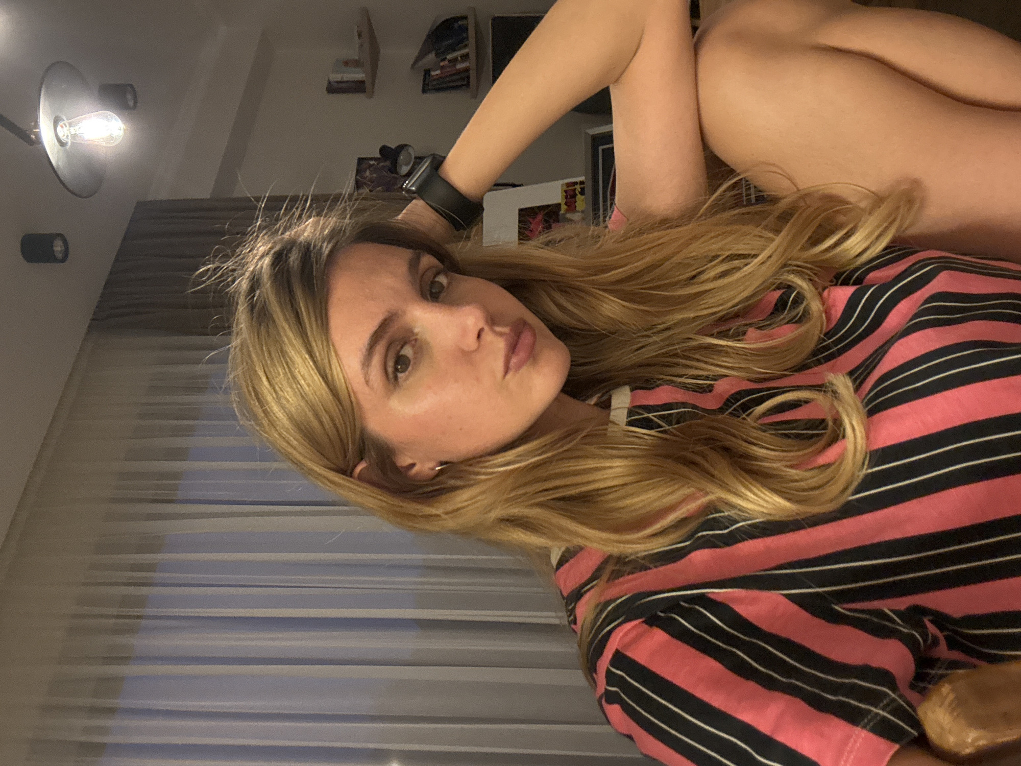 Woman takes indoor selfies in pink striped top